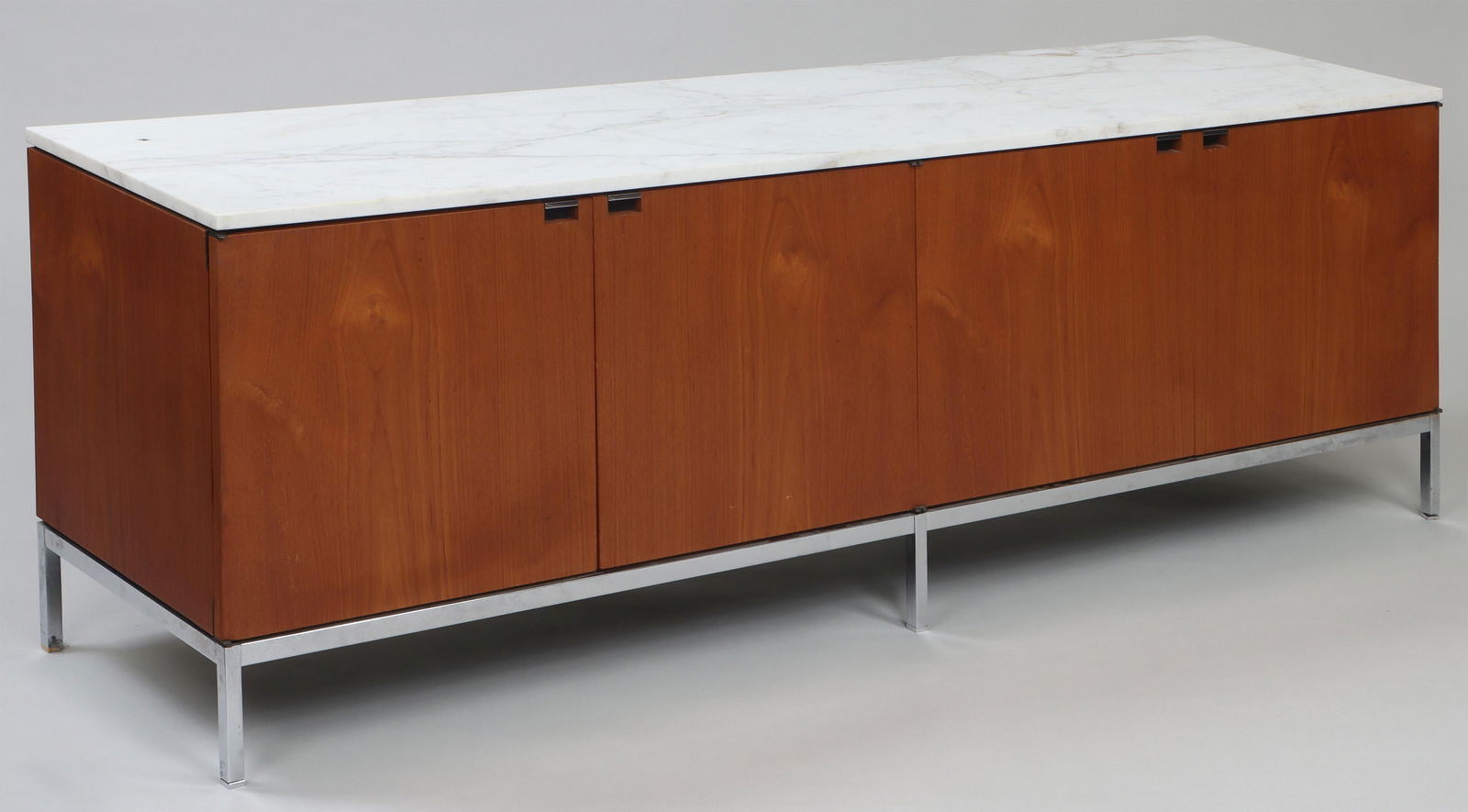 FLORENCE KNOLL (American, 1917-2019): FLORENCE KNOLL (American, 1917-2019), Knoll International, walnut-veneer and marble-top credenza, having four doors with fitted shelves, on chrome frame, with Knoll International label. Missing one in