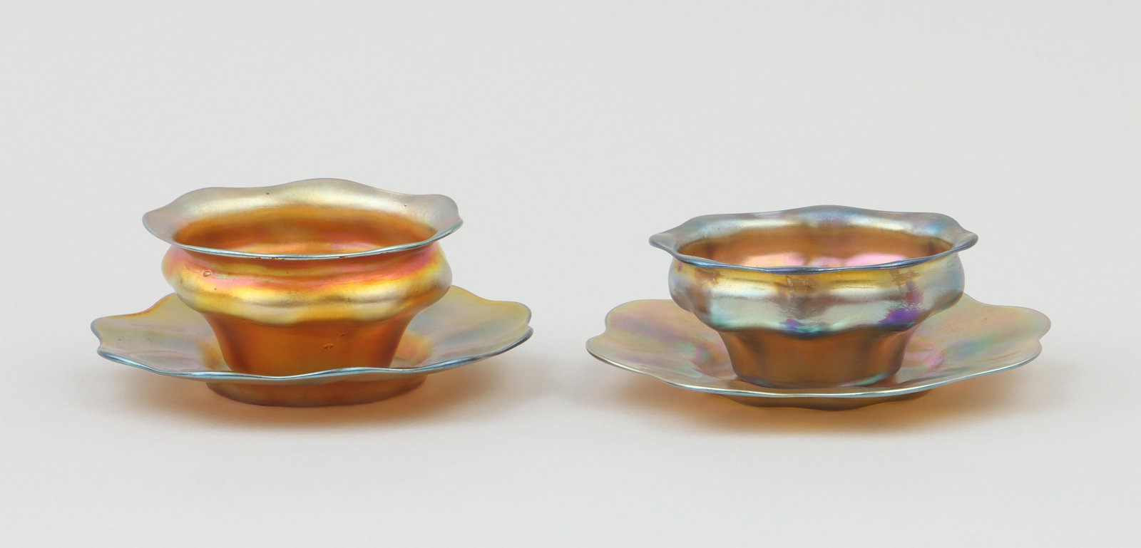 Group of (2) Tiffany favrile glass: Group of (2) Tiffany Studios favrile glass floriform bowls with underplates, all pieces signed ''L.C.T.'' on undersides, one bowl incised ''133'' or ''135''. Minor wear, one bowl having spots of wear 