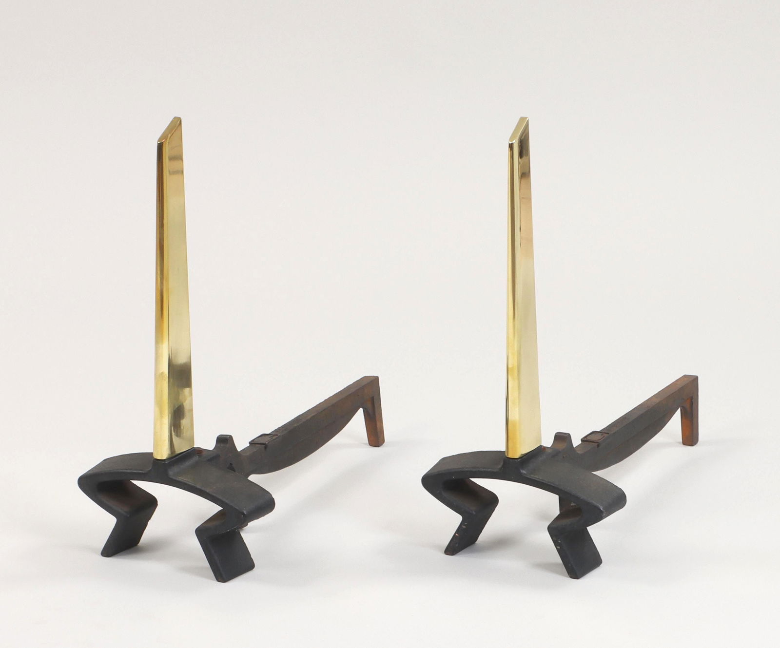 DONALD DESKEY (American, 1894-1989): DONALD DESKEY (American, 1894-1989) for Bennett, pair of andirons, 1950s, each with tapering brass blade on cast iron legs, embossed ''Bennett''. Minor scratches and wear to brass, minor oxidation on
