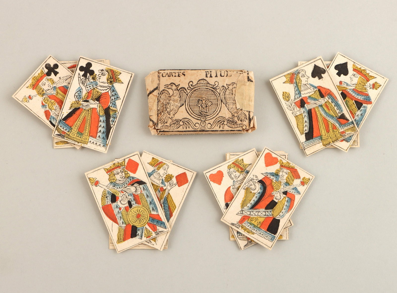 18C French piquet pack playing cards: 18th century French piquet pack of 32 playing cards, Lyon, circa 1760, having woodcut court cards with pochoir colors, in original laid paper wrapper with woodcut coat of arms flanked by two eagles. M