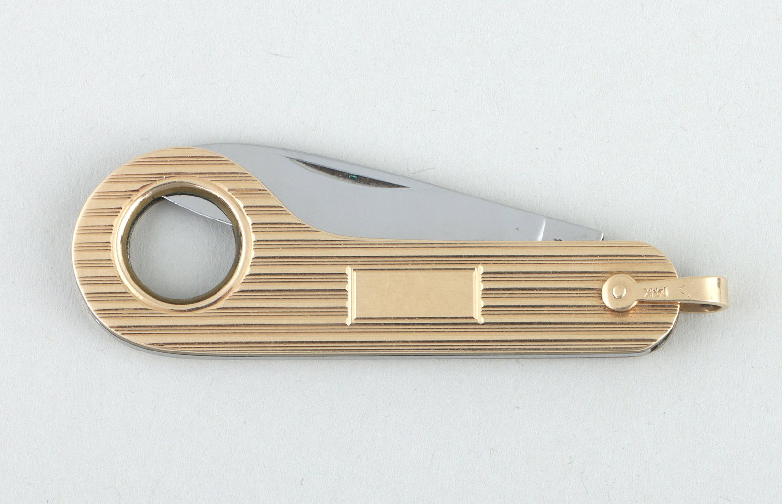 Tiffany & Co. 14k gold cigar cutter: Tiffany & Co. 14k gold cigar cutter, having stainless steel blade in 14k gold cover with reeded design, marked on loop. Minor wear. 2-1/2''l (closed).