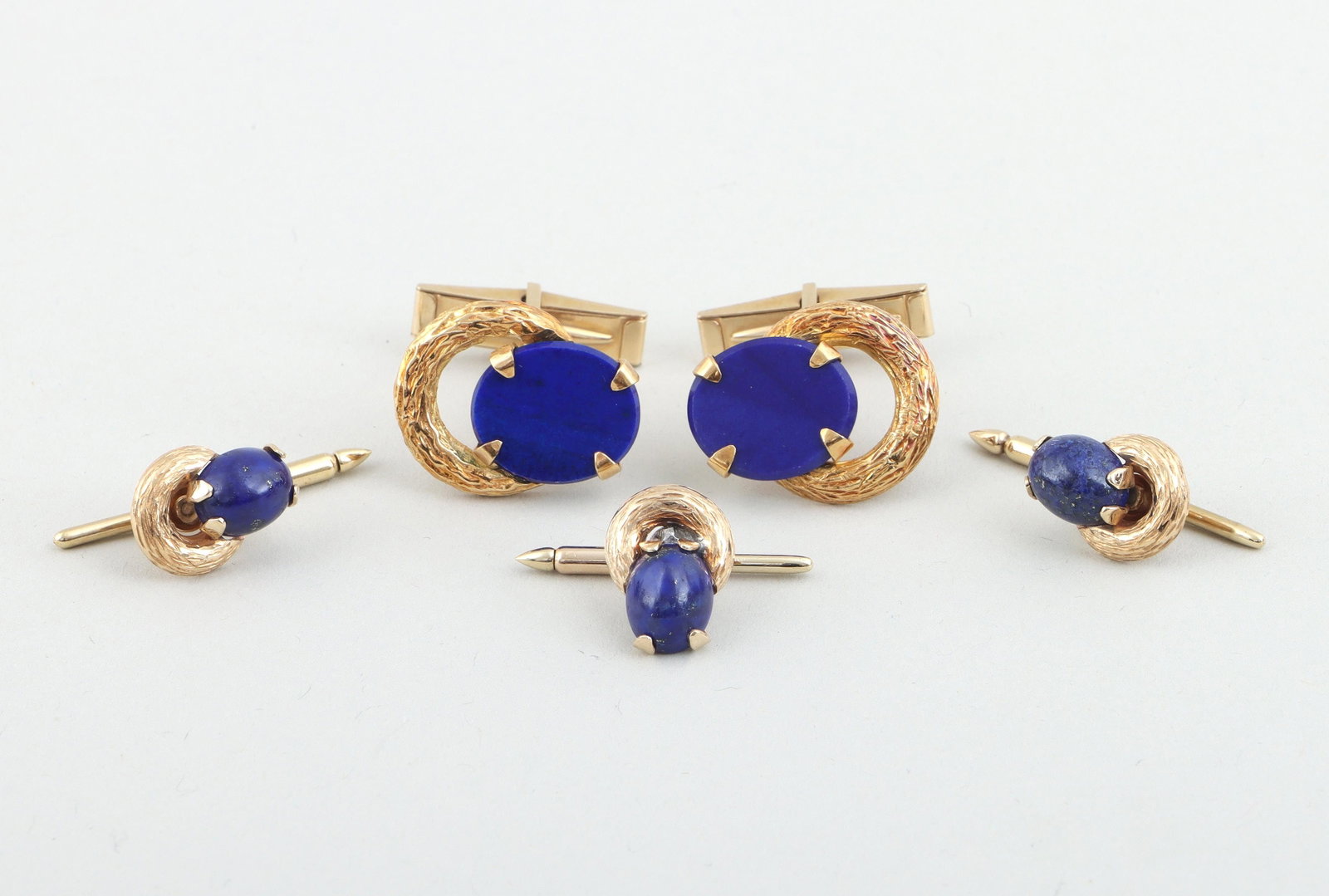 Set of (4) lapis lazuli and 14k gold jewelry: Lapis lazuli and 14k gold stud and cufflink set, all having a prong-set oval lapis lazuli stone over a textured gold ring, to include: a pair of toggle closure cufflinks with oval-cut stones on hinges