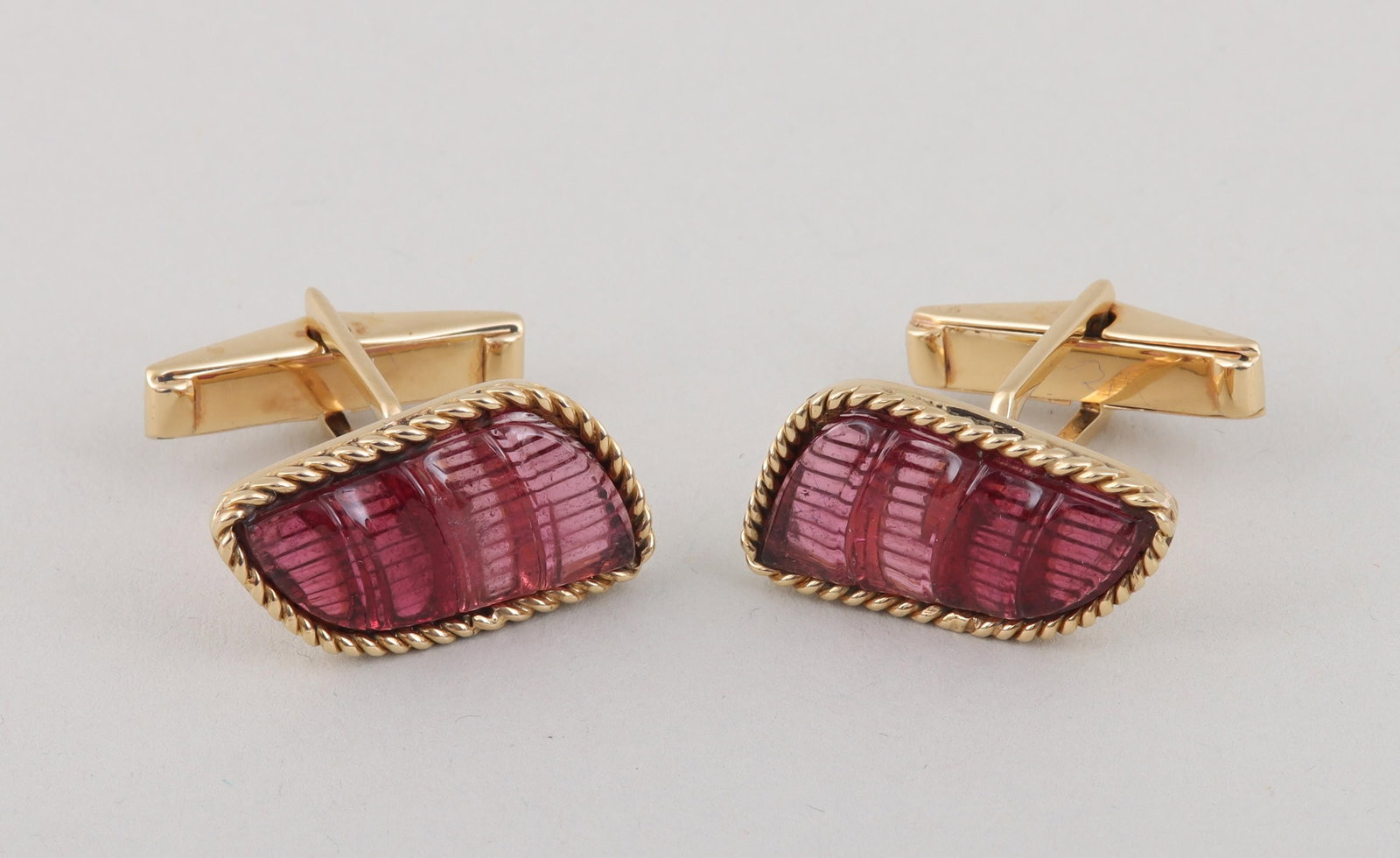 Pair of pink stone and 14k gold cufflinks: Pair of semi-precious pink stone and 14k gold cufflinks, having a faux-bamboo carved semi-precious pink stone in a hinged setting with 14k twist border, unmarked. 1/2''h, 7/8''w; approximate weight 8.