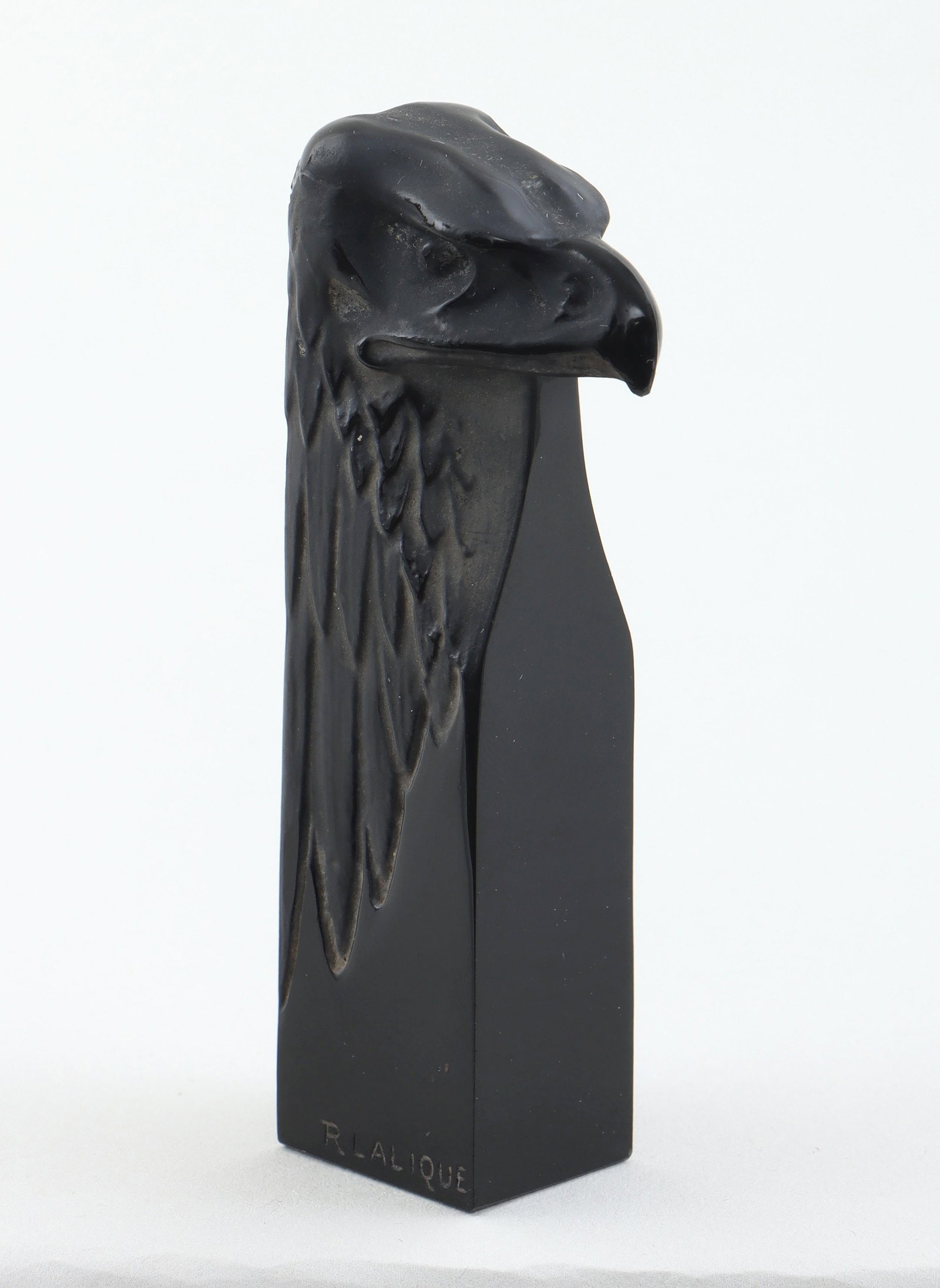 R. Lalique ''tete d'aigle'': R. Lalique ''tete d'aigle'' [eagle's head] glass seal, incised ''R Lalique'' at bottom of one side. Nick to back of eagle's head, minor scratches, minor dirt and grime. 3-3/16''h, 1-3/8''w, 11/16''d.
