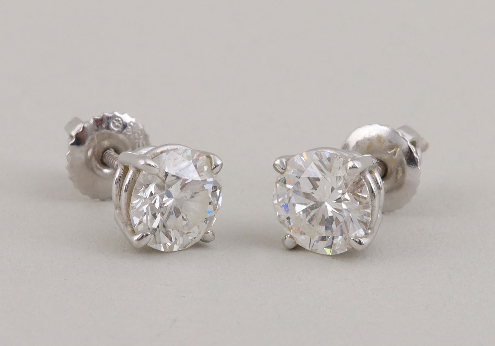 Pair of 1 carat diamond stud earrings: Pair of 1 carat diamond stud earrings, each having a round brilliant-cut diamond prong-set in 14k white gold, one diamond approximately 1.03 carats (SI1, G color), the other approximately 1.02 carats