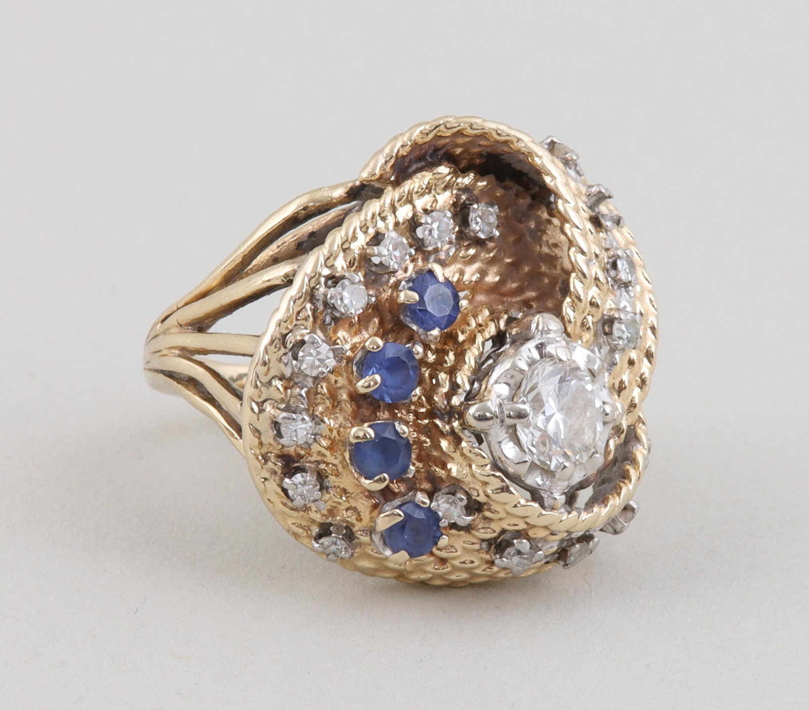 Diamond, sapphire and 14k gold cocktail ring: Diamond, sapphire and 14k gold knot cocktail ring, having gold knot with (23) prong-set precious stones on top, comprising an approximately 0.5 carat diamond (SI2, I color), (4) round-cut sapphires an