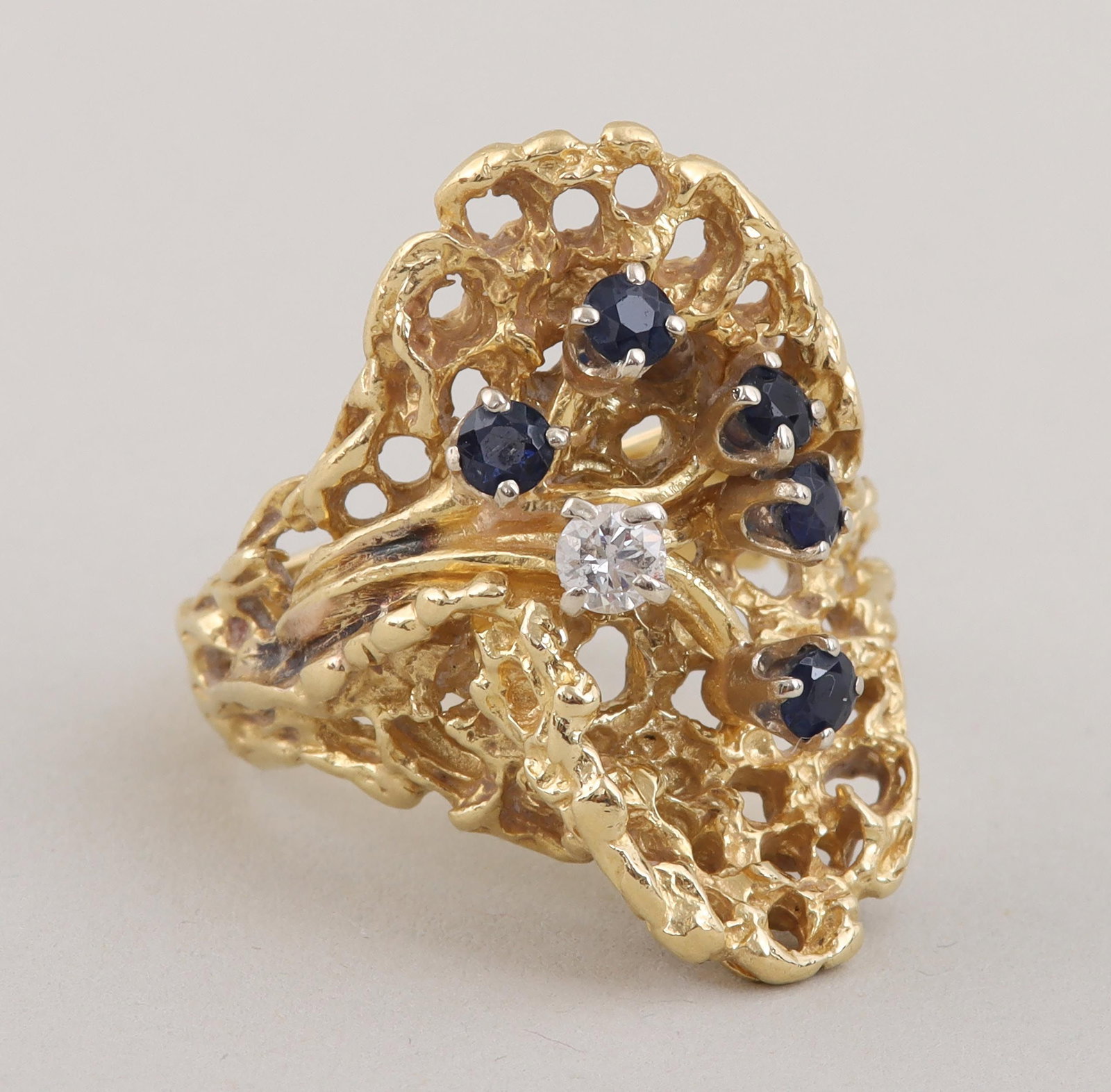Sapphire, diamond and 18k gold ring: Sapphire, diamond and 18k gold cocktail ring, having (4) round-cut sapphires and a round-cut diamond prong-set over a reticulated gold oval, marked inside band. Minor wear, minor dirt and grime. Ring 
