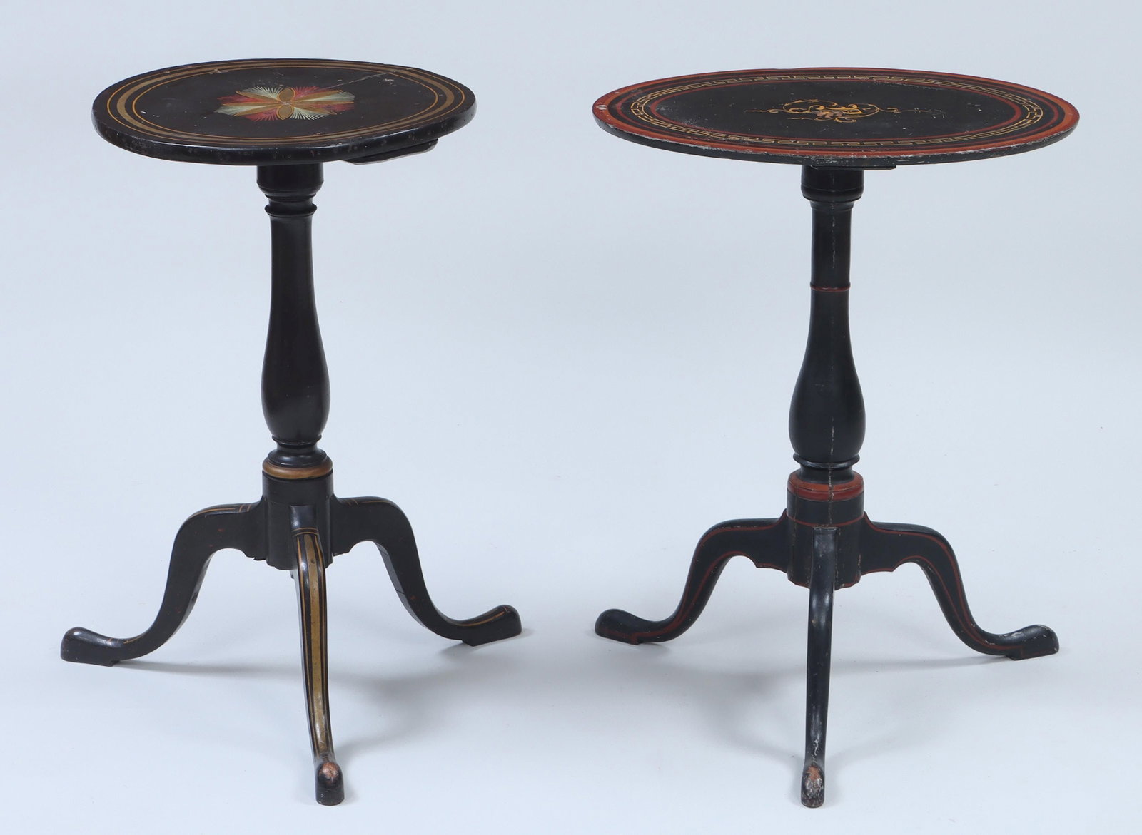 Group of (2) black painted candle stands: Group of (2) black-painted candlestands with baluster turned standard on tripod base, to include: oval-top stand having red line and gilt Greek key border with gilt letter at center; and circular top 