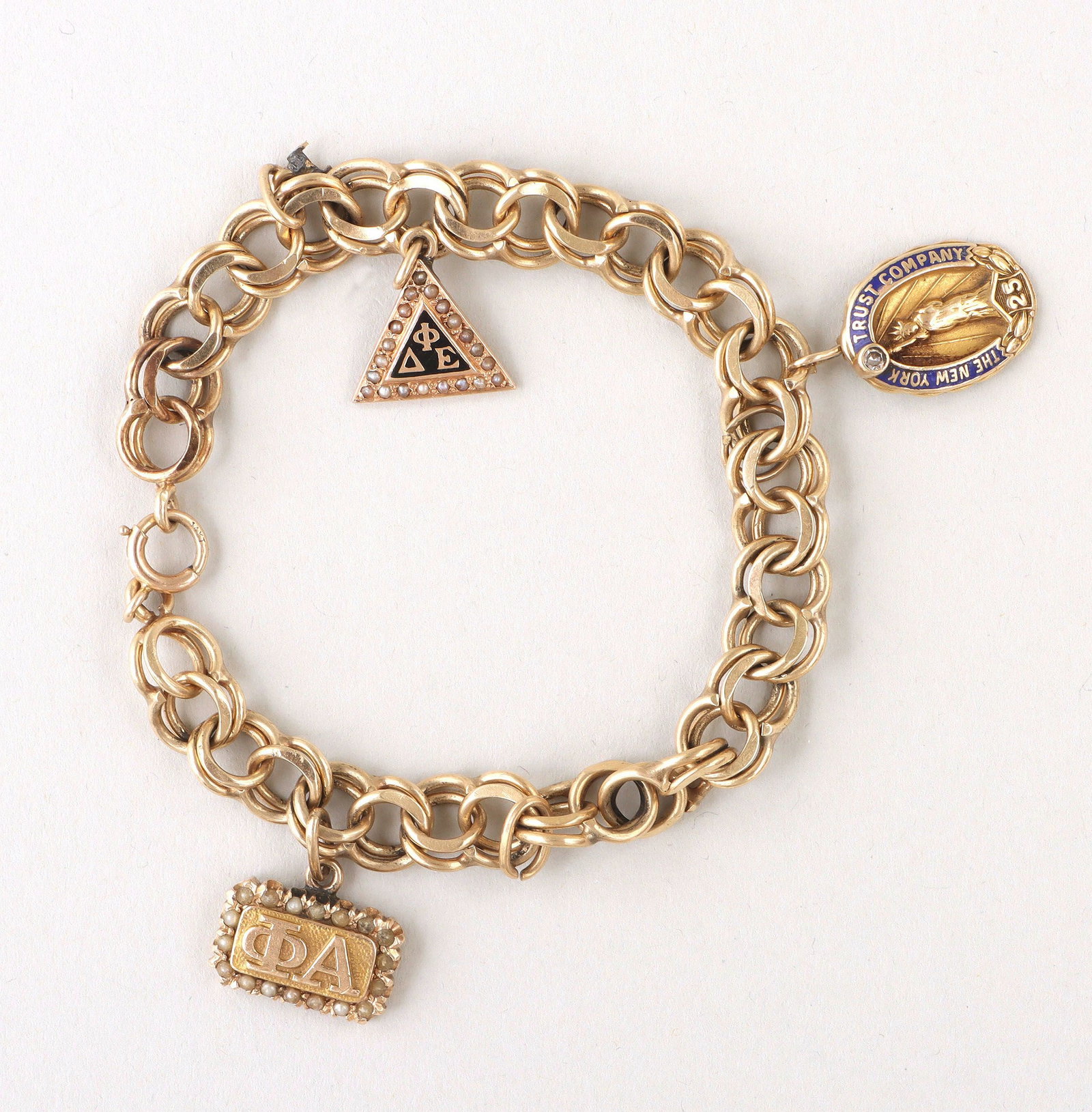 14k gold charm bracelet: 14k gold charm bracelet having parallel chain with (3) early 20th century charms, charms to include: The New York Trust Company 25th anniversary charm having Statue of Liberty with diamond on end of t