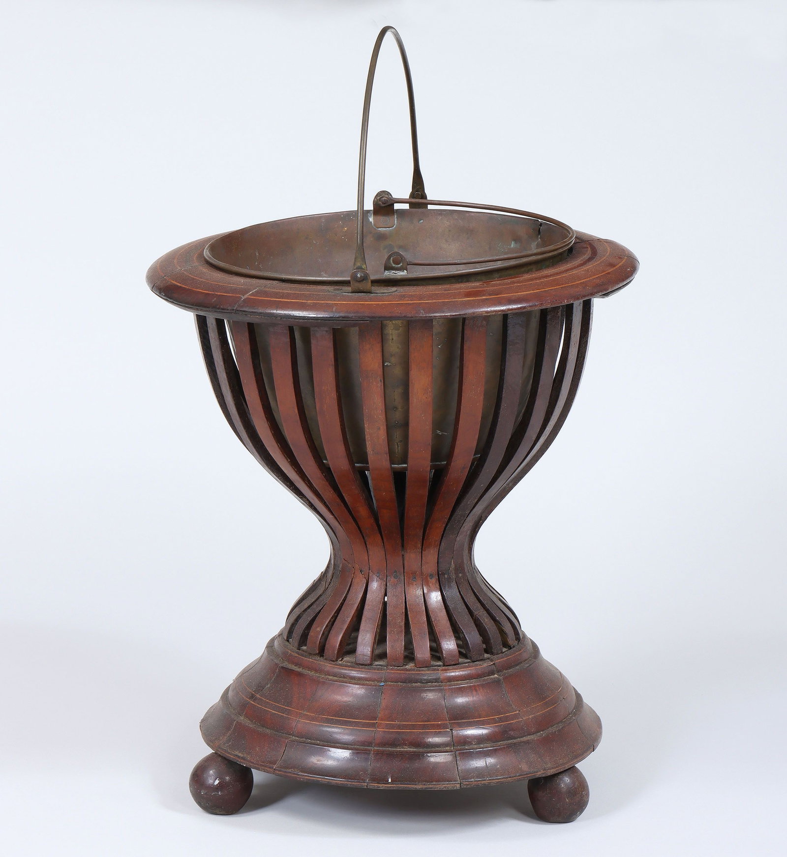Regency mahogany peat pail: Regency mahogany peat pail, having fruitwood line inlay, brass swing-handle, openwork body, and copper swing-handled bucket insert, on three ball feet. Splits and repairs. 16-3/4''h, 15''dia.
