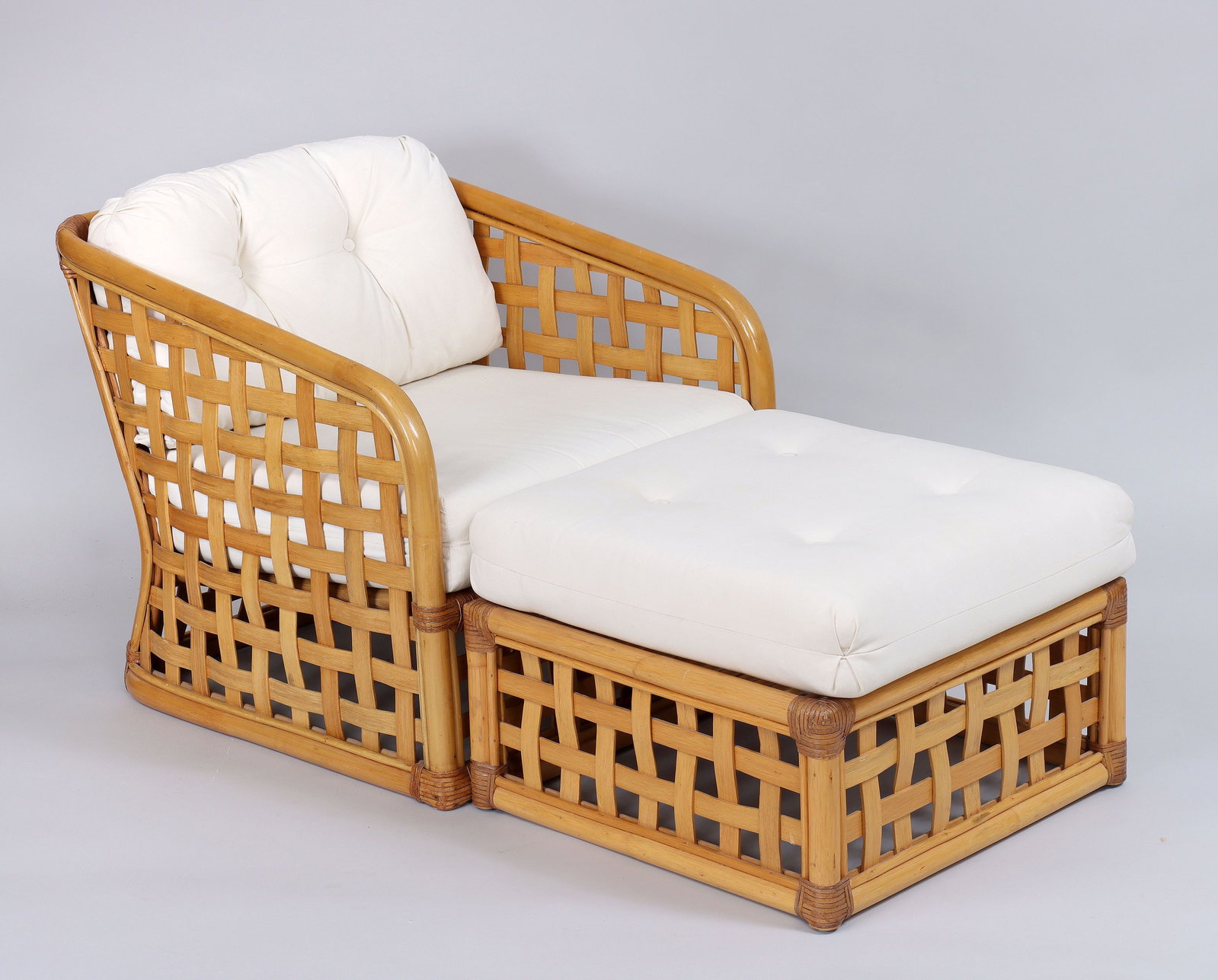 Bamboo armchair and ottoman: Bamboo armchair and ottoman with basketweave sides and back, and leather wrapping to corners, white cushions, mid-20th century. Minor stains to cushions. 27''h, 27''w, 32''d.