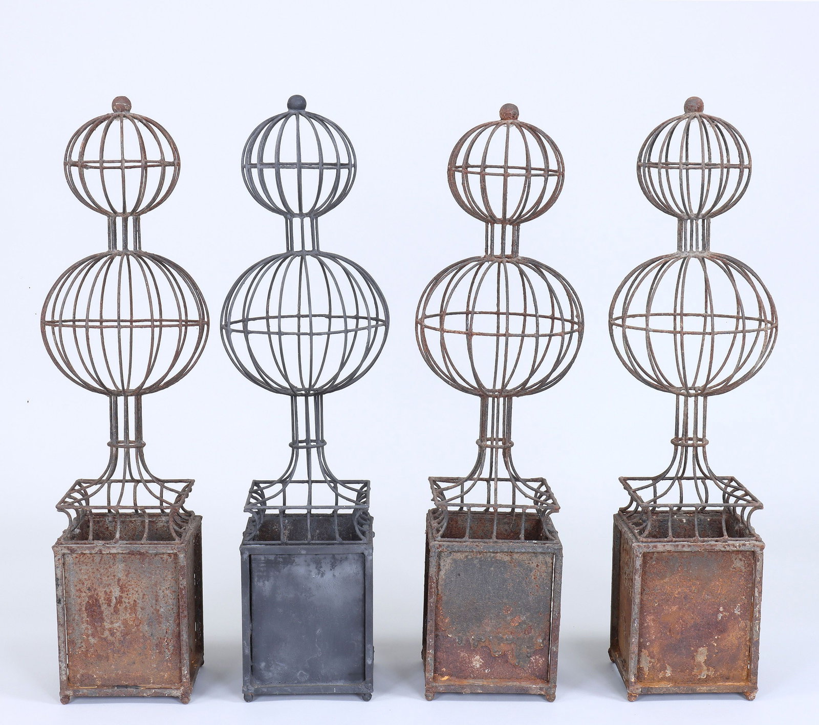 Set of (4) iron topiaries: Set of (4) iron topiaries, each with graduated double globe tops and box bases. Three weathered with rust. 31-3/4''h.