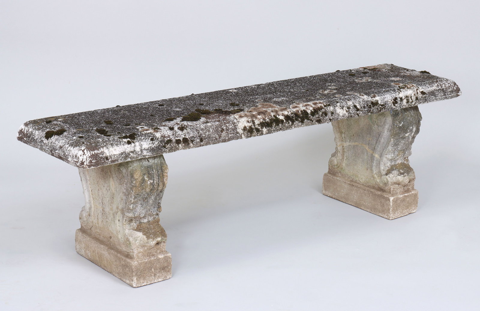 Cast stone garden bench: Cast stone garden bench with long rectangular seat set on two supports with acanthus leaf and scroll decoration. Weathered. 18-1/2''h, 60''w, 15''d.