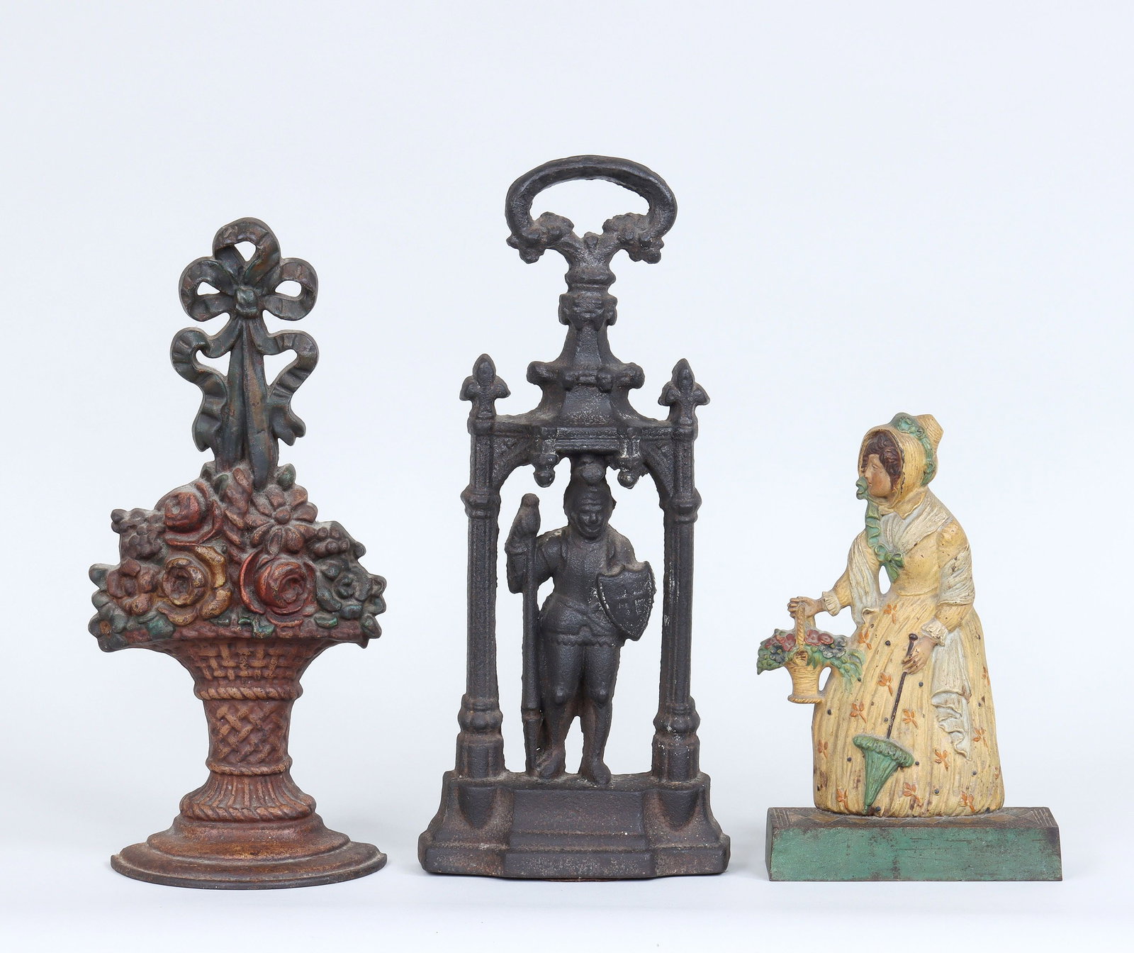 Group of (3) cast iron doorstops: Group of (3) cast iron doorstops, to include: Bradley & Hubbard polychrome-painted woman with parasol, marked ''B&H'' to reverse; polychrome-painted flower basket, (paint loss); and black-painted knig