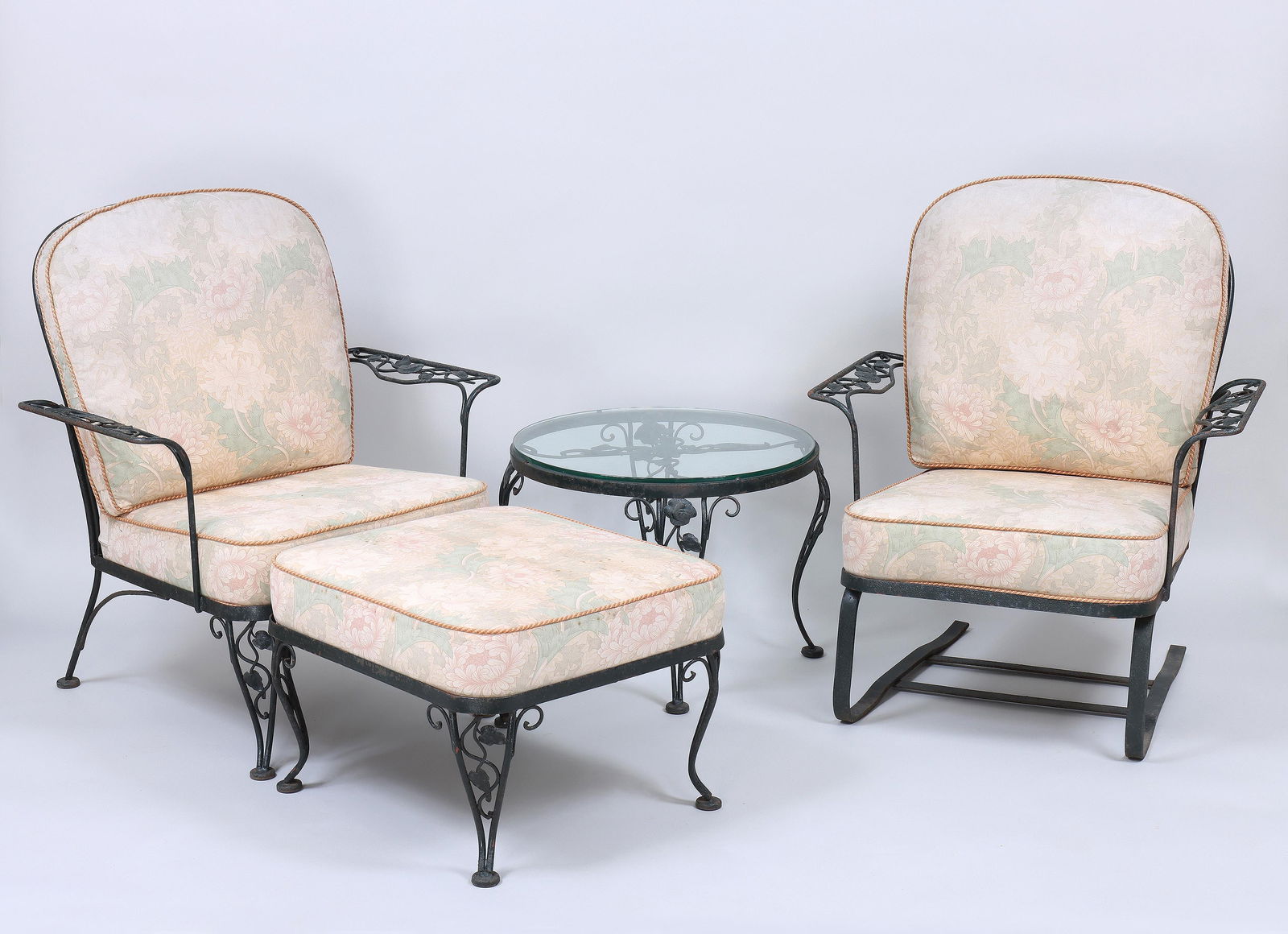 Four-Piece Wrought Iron Patio Set: Four-Piece Wrought Iron Patio Setwith rose vine accents, to include: lounge armchair, ottoman, spring rocking armchair, and small circular glass-top side table.Armchair 35 3/4 x 31 x 28 1/4 in. (90.8