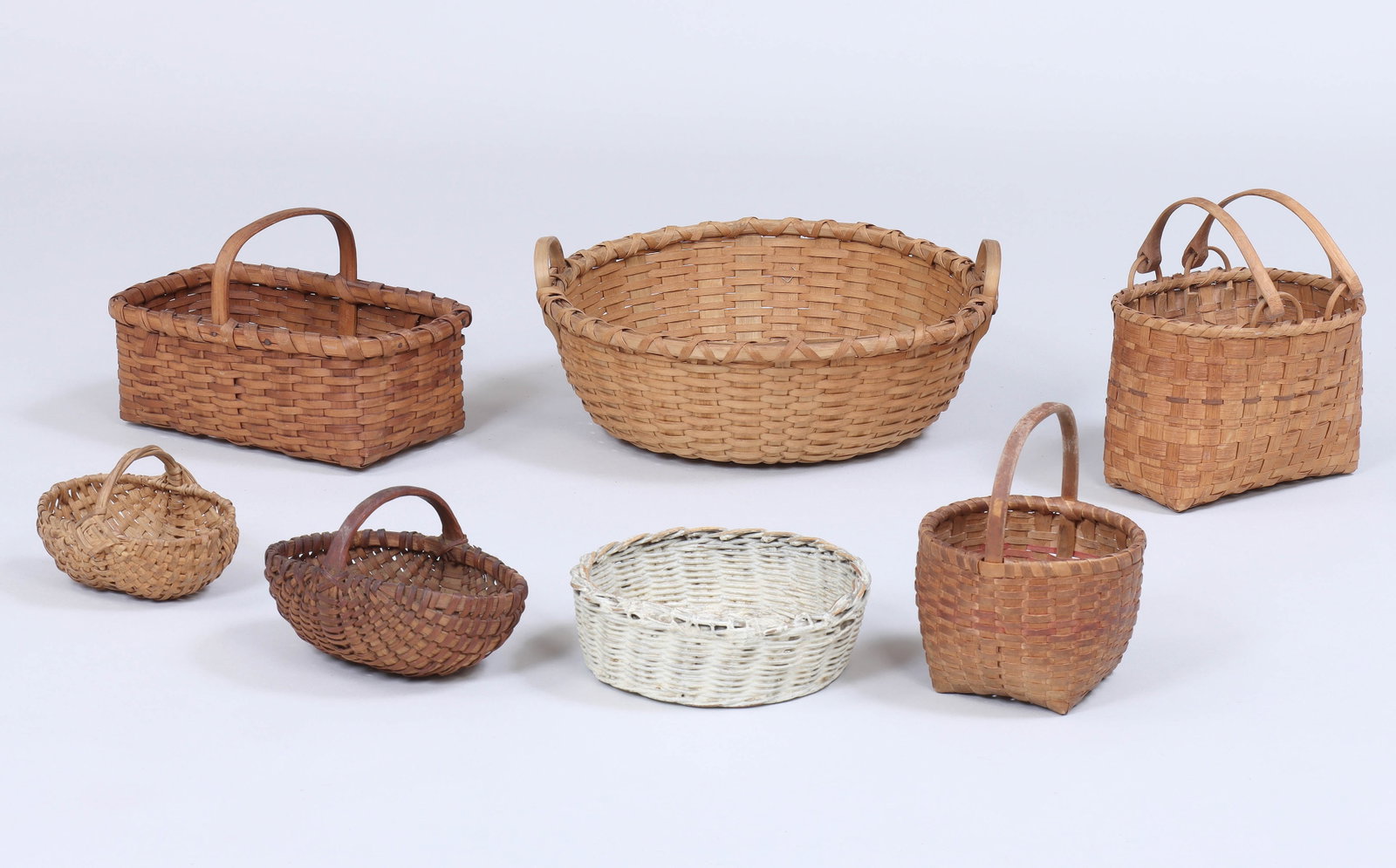 Group of (7) Woven Splint Baskets: Group of (7) Woven Splint Baskets to include: basket with two swing handles and paint-decorated splints; cat’s head basket with paint-decorated splints and fixed handle; large round two-handled bask