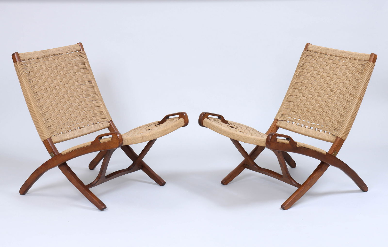 Pair of Hans Wegner-style Folding Chairs: Pair of Hans Wegner-style Folding Chairswalnut with woven rope seat and backrest, marked "Yugoslavia" to underside.Extended 29 x 23 1/2 x 30 1/2 in. (73.7 x 59.7 x 77.5 cm.) Provenance: Prop
