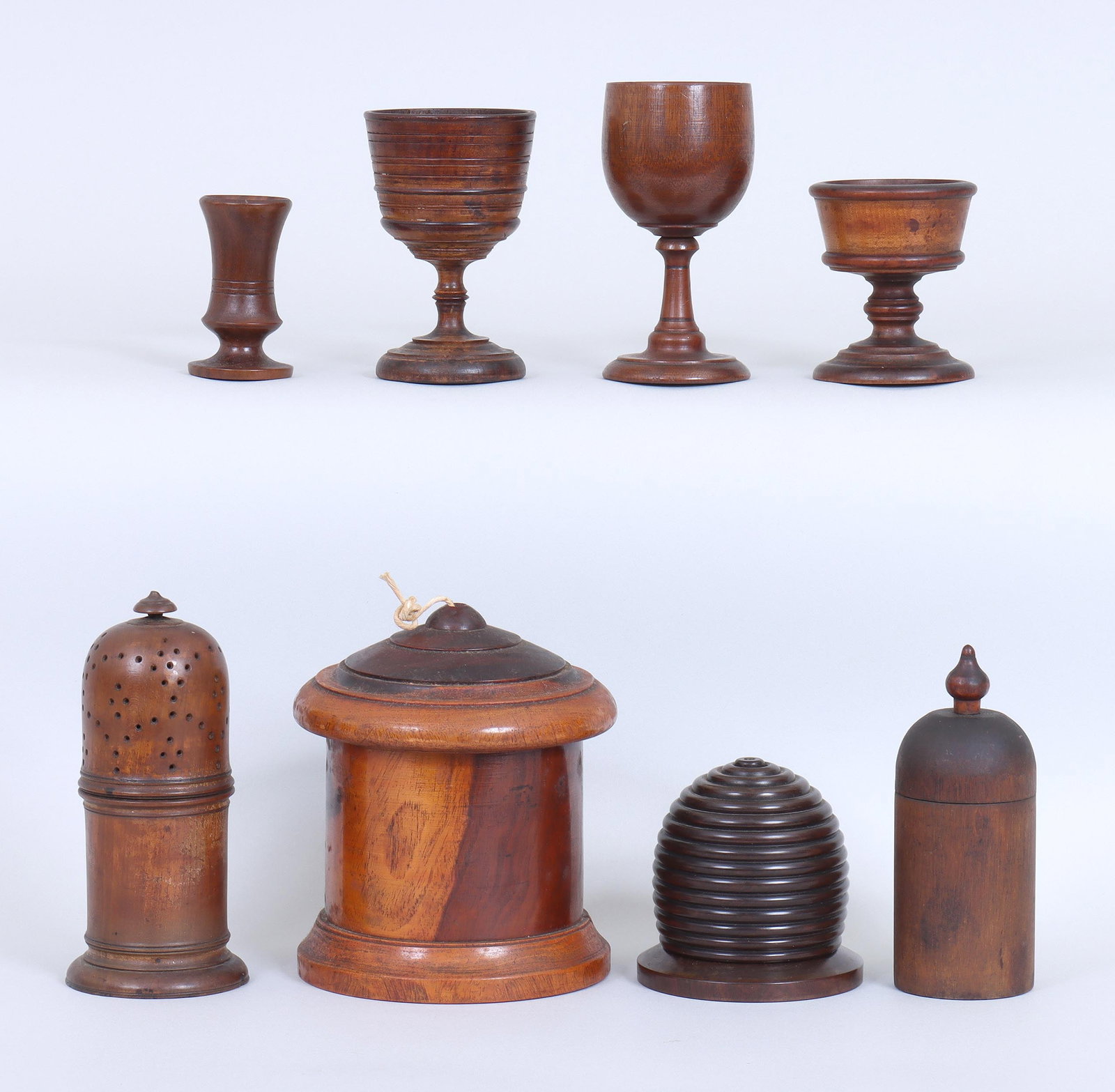 Group of (8) Treen Items: Group of (8) Treen Items to include: (2) string dispensers, the larger with a cylindrical body, and the smaller in the form of a beehive; muffineer or shaker; covered vessel, having lid with finial; (