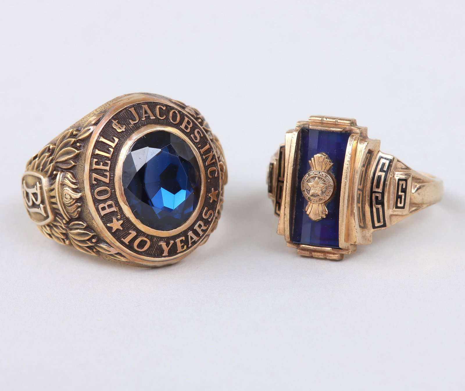 Group of (2) 10k Gold Commemorative Rings: Group of (2) 10k Gold Commemorative Rings each with a blue topaz or spinel, to include: William Horlick High School class ring, having rectangular-cut stone with school emblem applied on top, the shou
