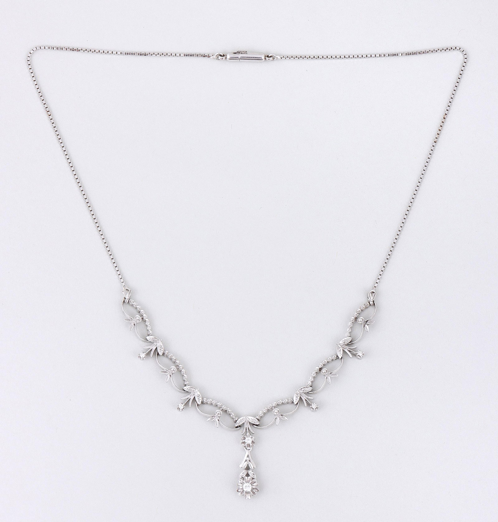 18k White Gold Festoon Necklace with Diamonds: 18k White Gold Festoon Necklace with Diamonds having floral and foliate pendant with (2) round-cut diamonds in buttercup settings, flanked by a series of floral and foliate chain links with (4) round-
