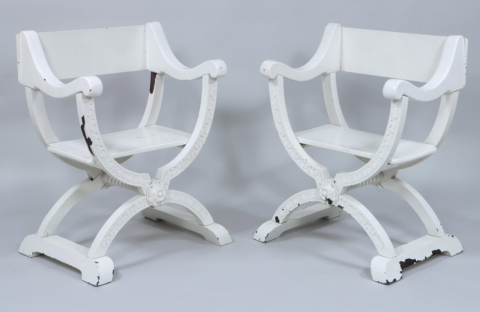 Pair of White-Painted Wood Curule Chairs: Pair of White-Painted Wood Curule Chairsthe supports with foliate designs in relief and central rosette.36 x 29 x 21 1/4 in. (91.4 x 73.7 x 54 cm.)