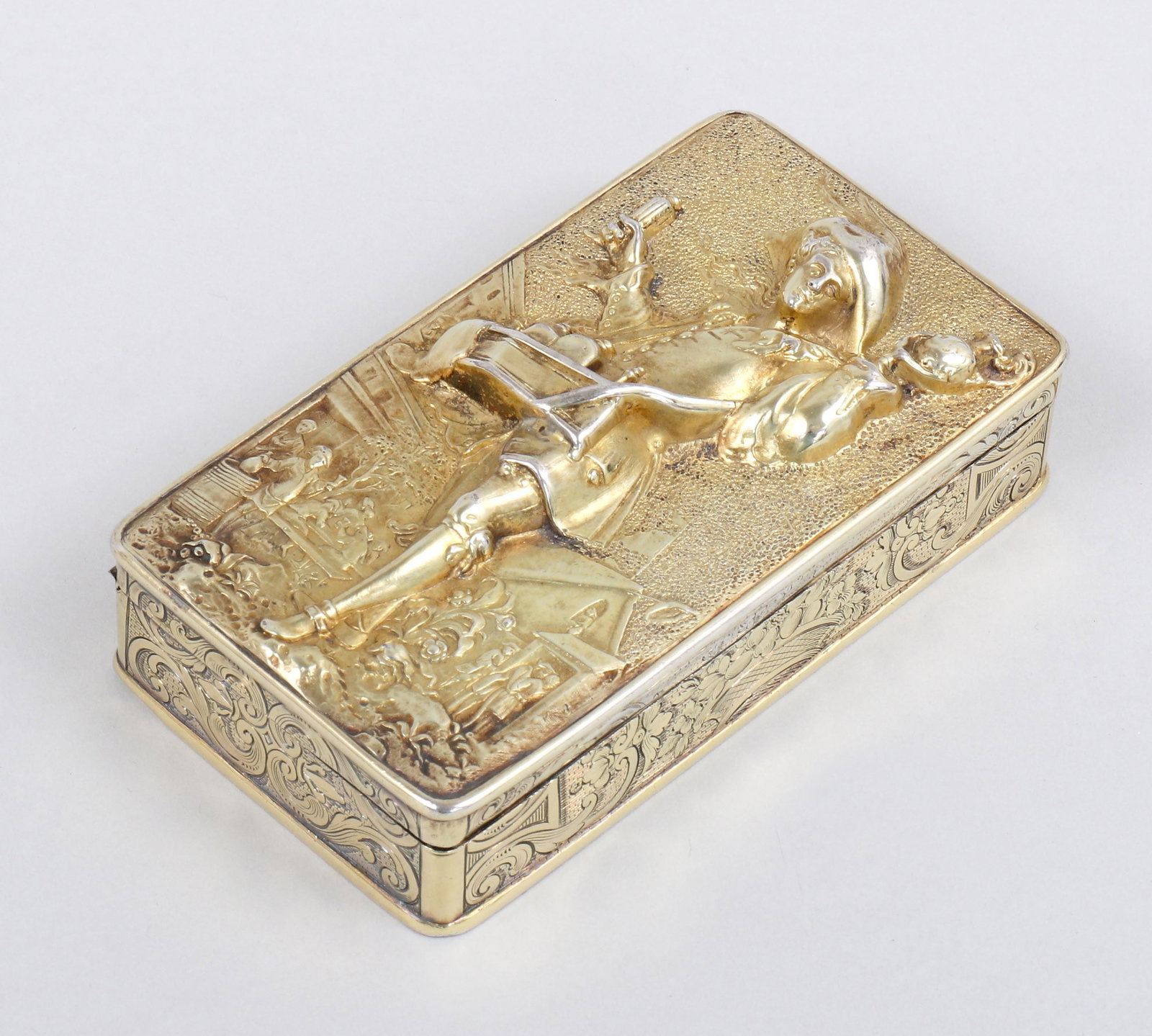 Georgian sterling silver gilt snuff box with wine peddler.: Georgian sterling silver gilt snuff box with wine peddler. Probably John Linnit, London, 1820, of rectangular form, the hinged cover relief-decorated with wine peddler in a townscape, the sides and bo
