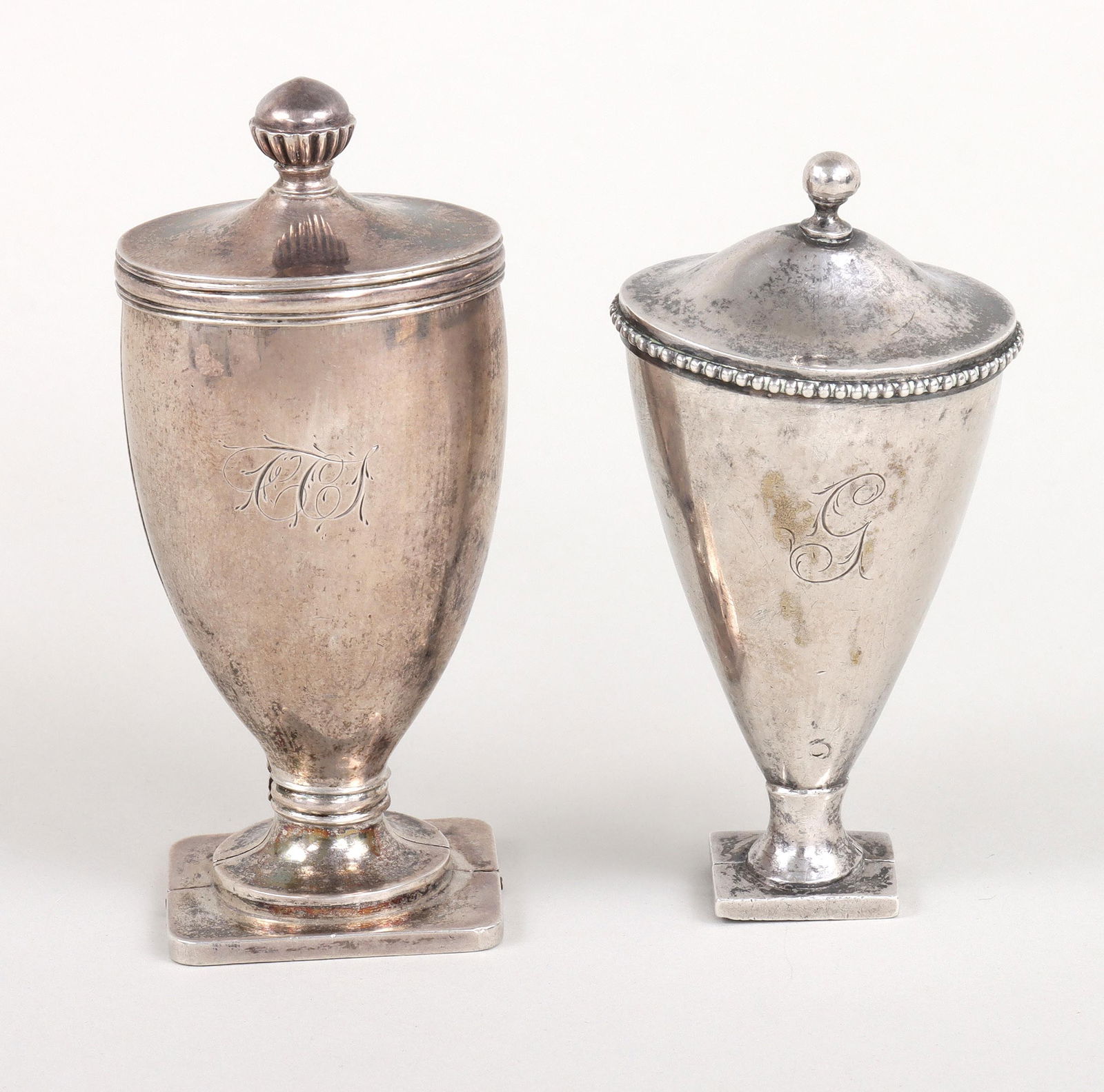 Group of (2) silver urn-form nutmeg graters.: Group of (2) silver urn-form nutmeg graters.Possibly English, 18th/19th century, each in silver case with hinged lid and hinged base allowing the front half of the body to open downward, revealing a p