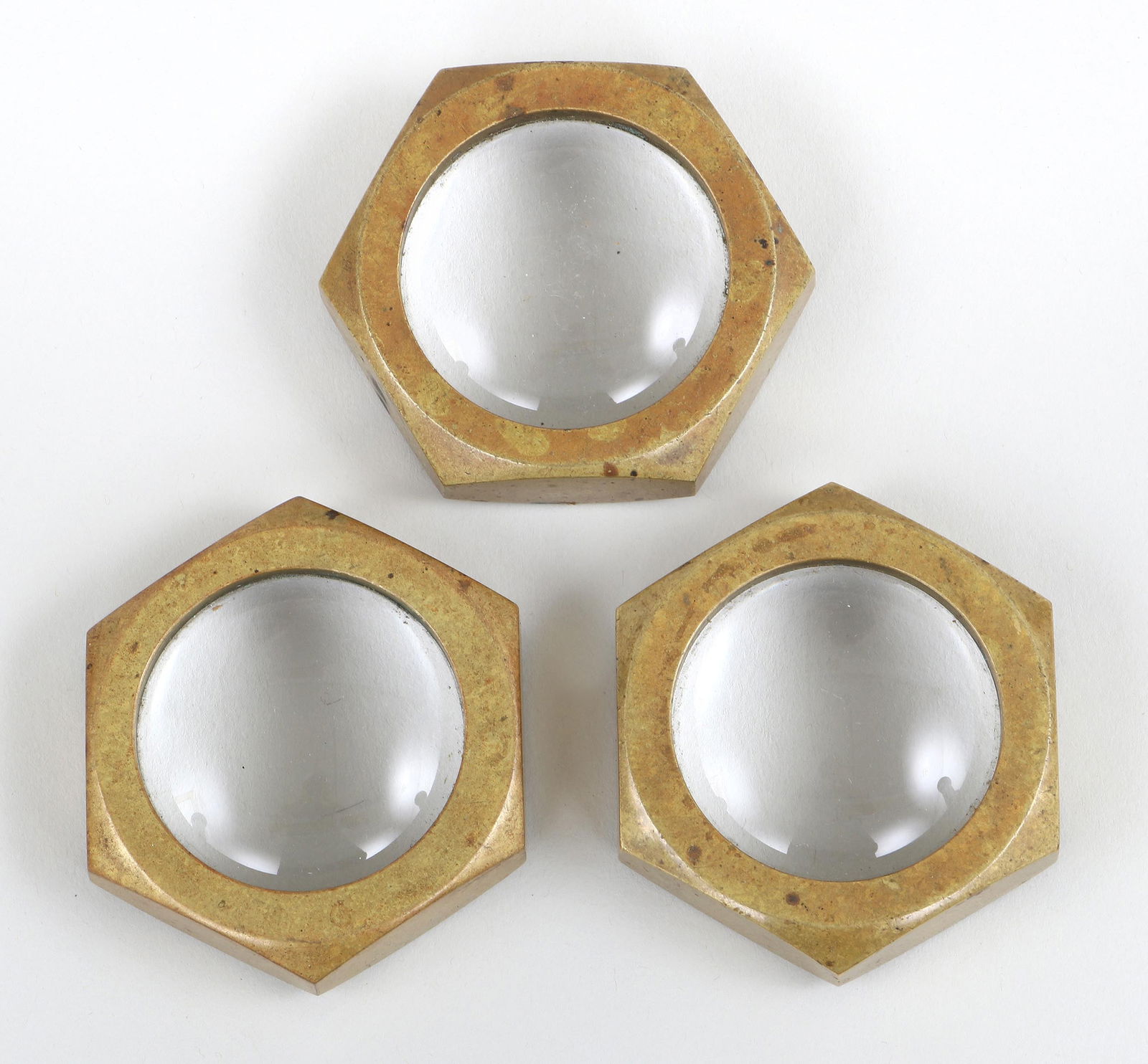 Carl Aubock Brass Paperweights with Magnifying Glasses: Set of (3) Carl Aubock Brass Paperweights with Magnifying GlassesAustria, c. 1960smodel 5071, in the form of hex nuts, each with round magnifying glass at center, marked on bottoms.2 7/8 x 2 1/2 in. (
