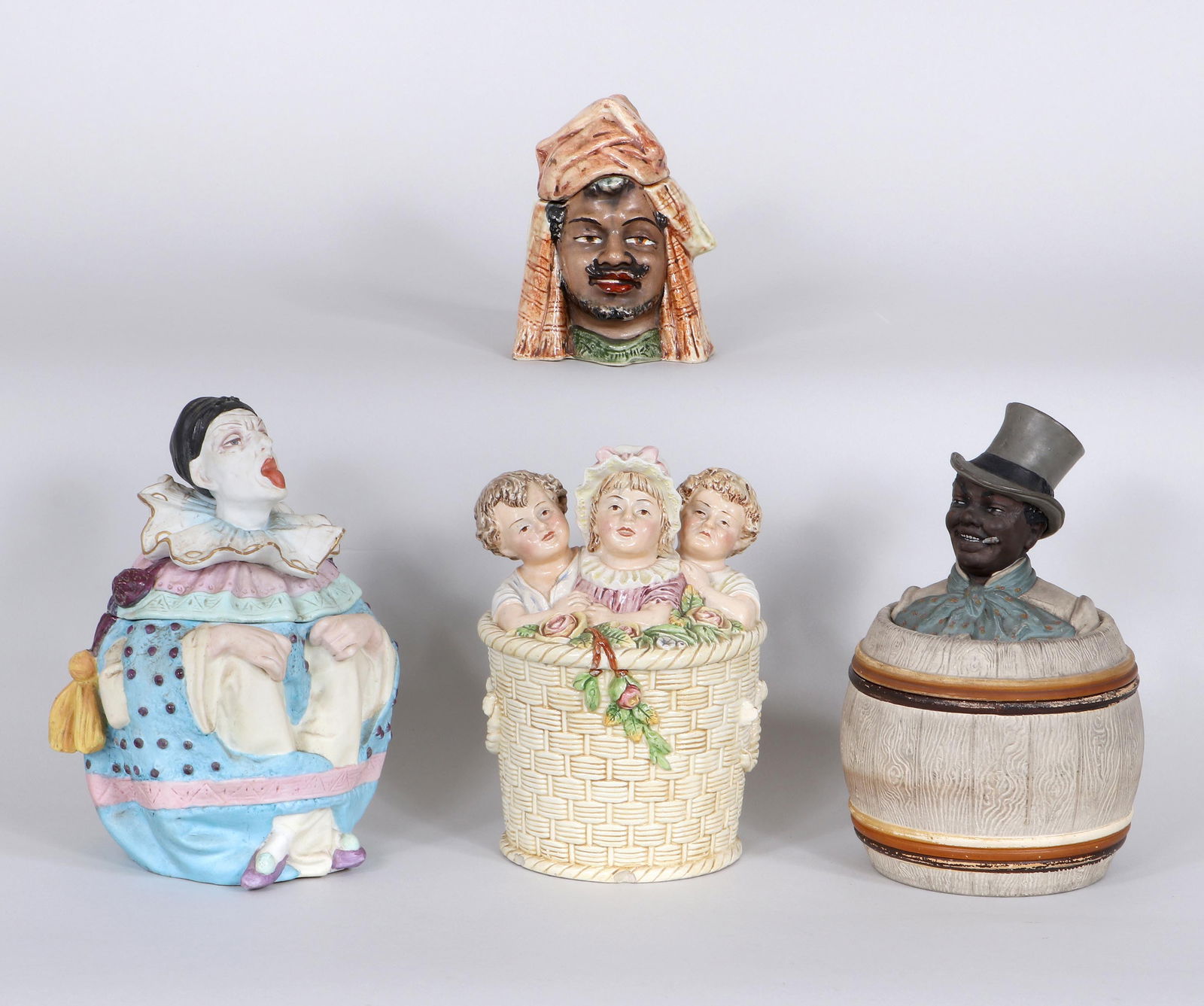 Figural Ceramic Humidors or Tobacco Jars: Group of (4) Figural Ceramic Humidors or Tobacco Jarsto include: Johann Maresch jar having a black man in a top hat emerging from a barrel, bottom impressed "JM" and numbered "3329"; humidor having th