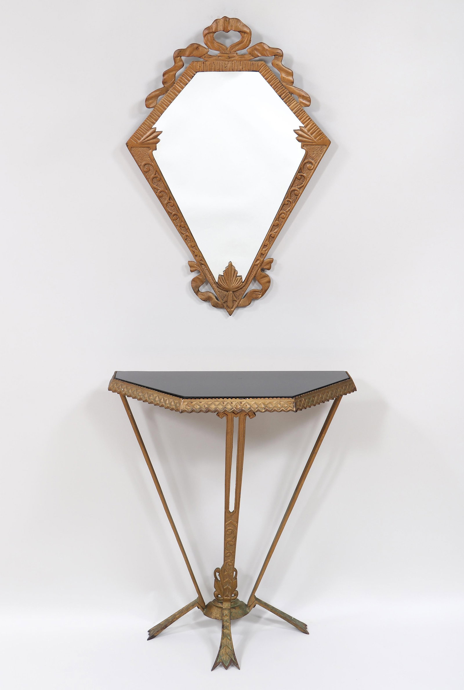 Art Deco Cast Iron Hall Stand and Mirror: Art Deco Cast Iron Hall Stand and Mirror in gold paint, the polygonal mirror with a ribbon crest, the demi-hexagonal stand having a black glass top, on tapering tripod legs ending in stylized trifid f