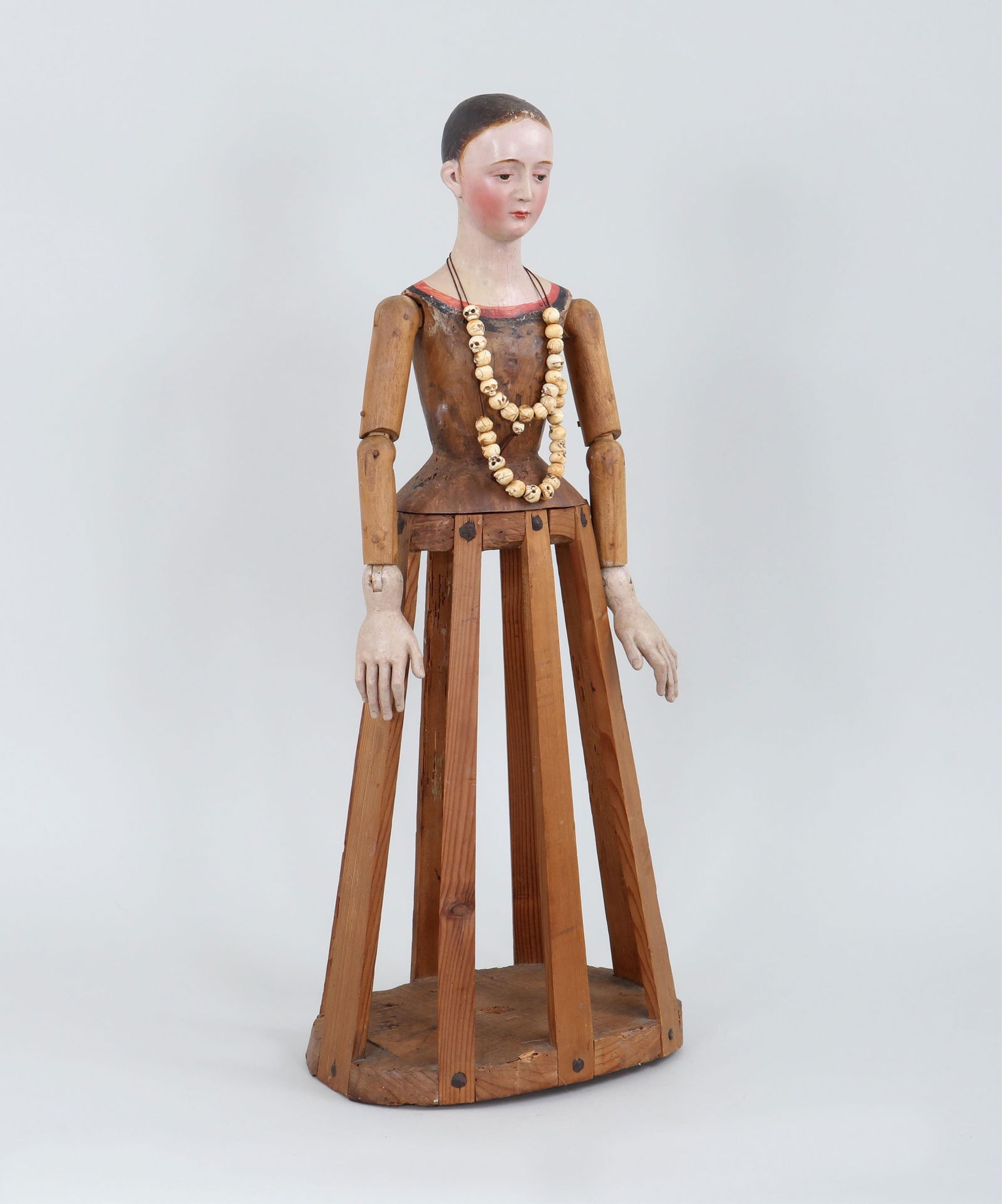 19th Century Cage Doll: 19th Century Cage Dollc. 1800, having torso with articulated arms, polychrome paint decoration, and added memento mori skull bead necklace.29 3/8 x 11 7/8 x 8 1/2 in. (74.6 x 30.2 x 21.6 cm.)