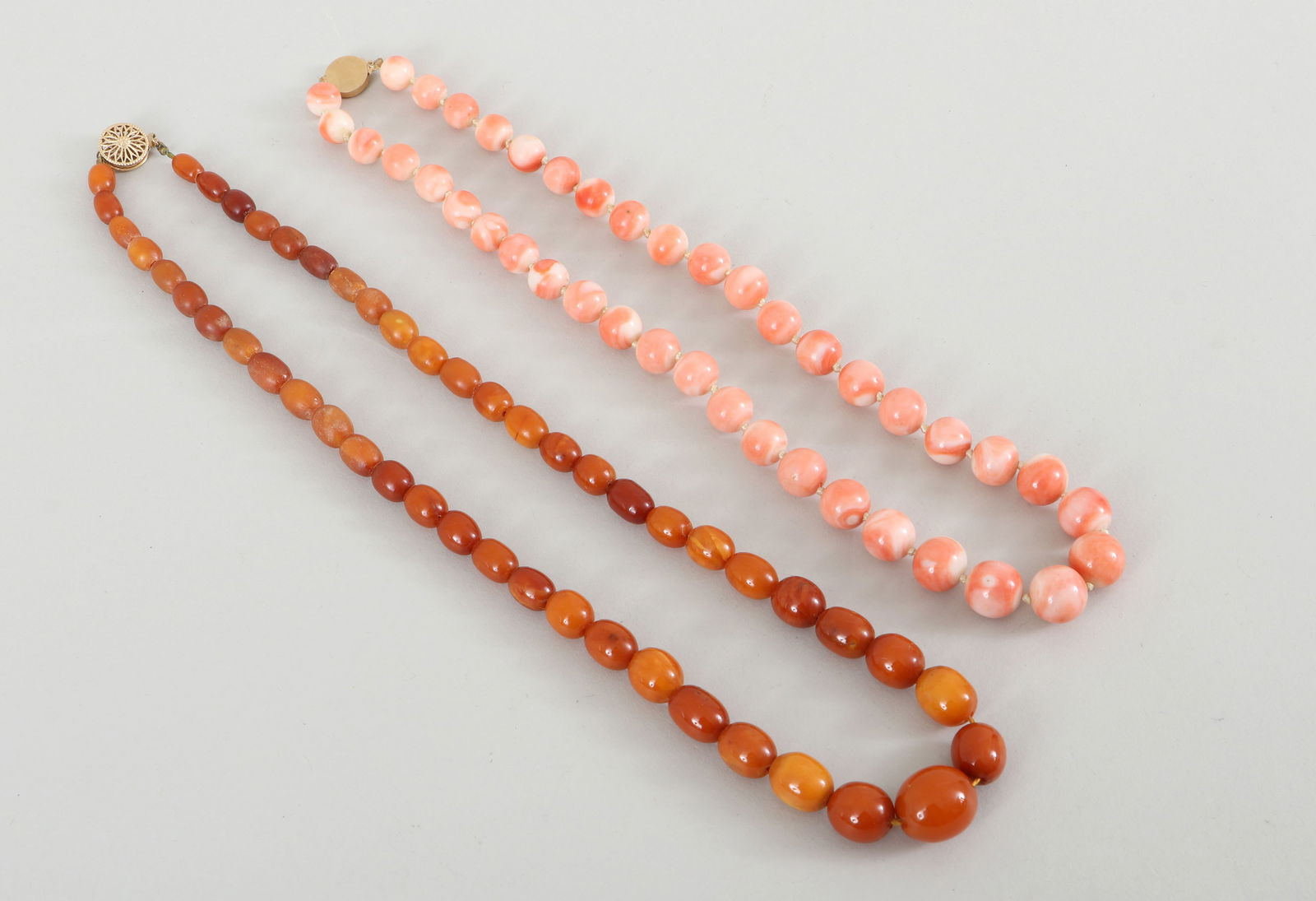 Group of (2) Coral and Amber Bead Necklaces: Group of (2) Coral and Amber Bead Necklaceswith 14k gold box clasps of round form and beads of graduated size, to include: coral necklace, with round beads ranging from approximately 9mm in diameter t
