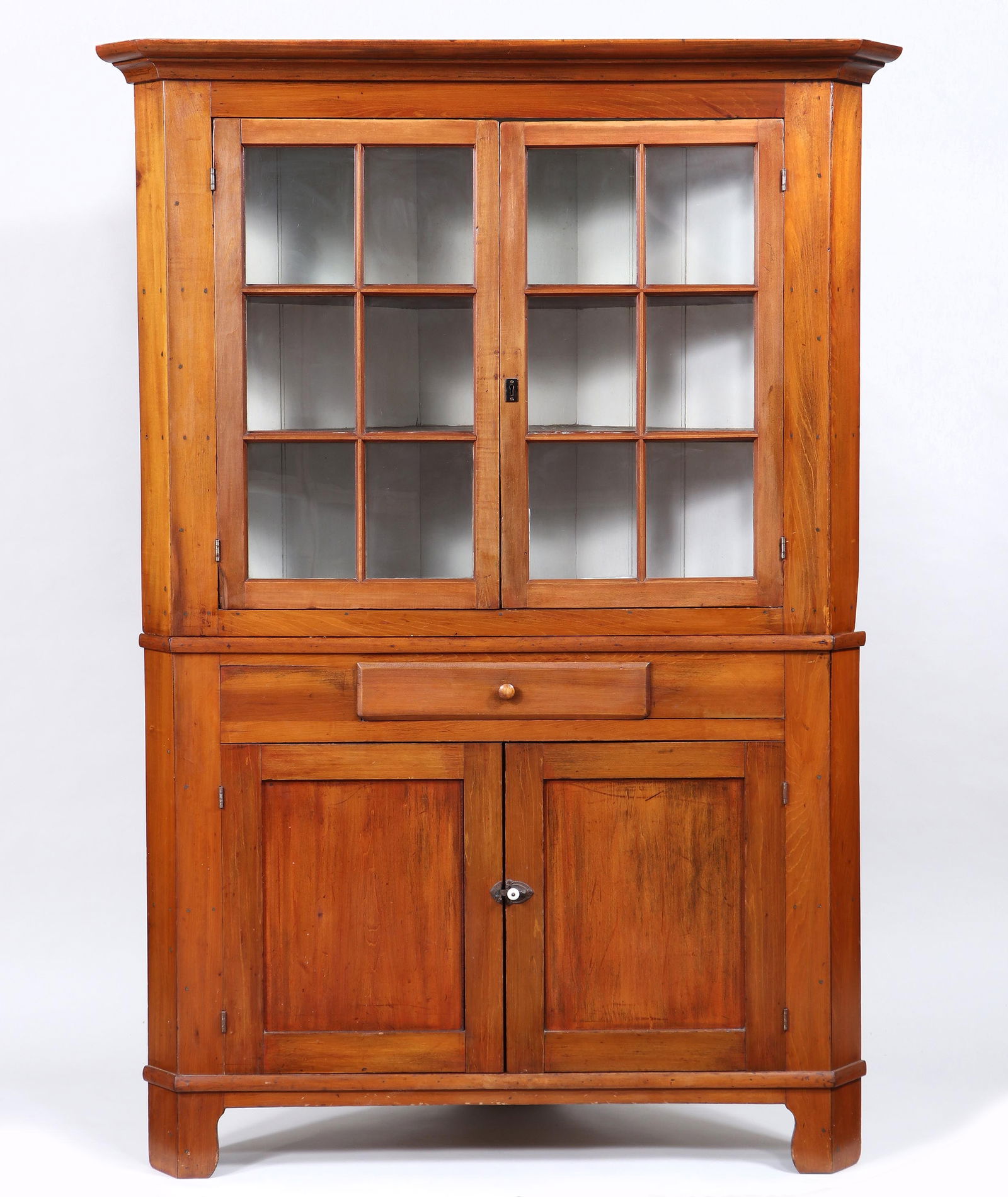 19th Century American Country Corner Cupboard: 19th Century American Country Corner Cupboardpine, in two parts, the top having a molded cornice over double-glazed doors opening to three shelves, the bottom with a drawer surmounting a cabinet with