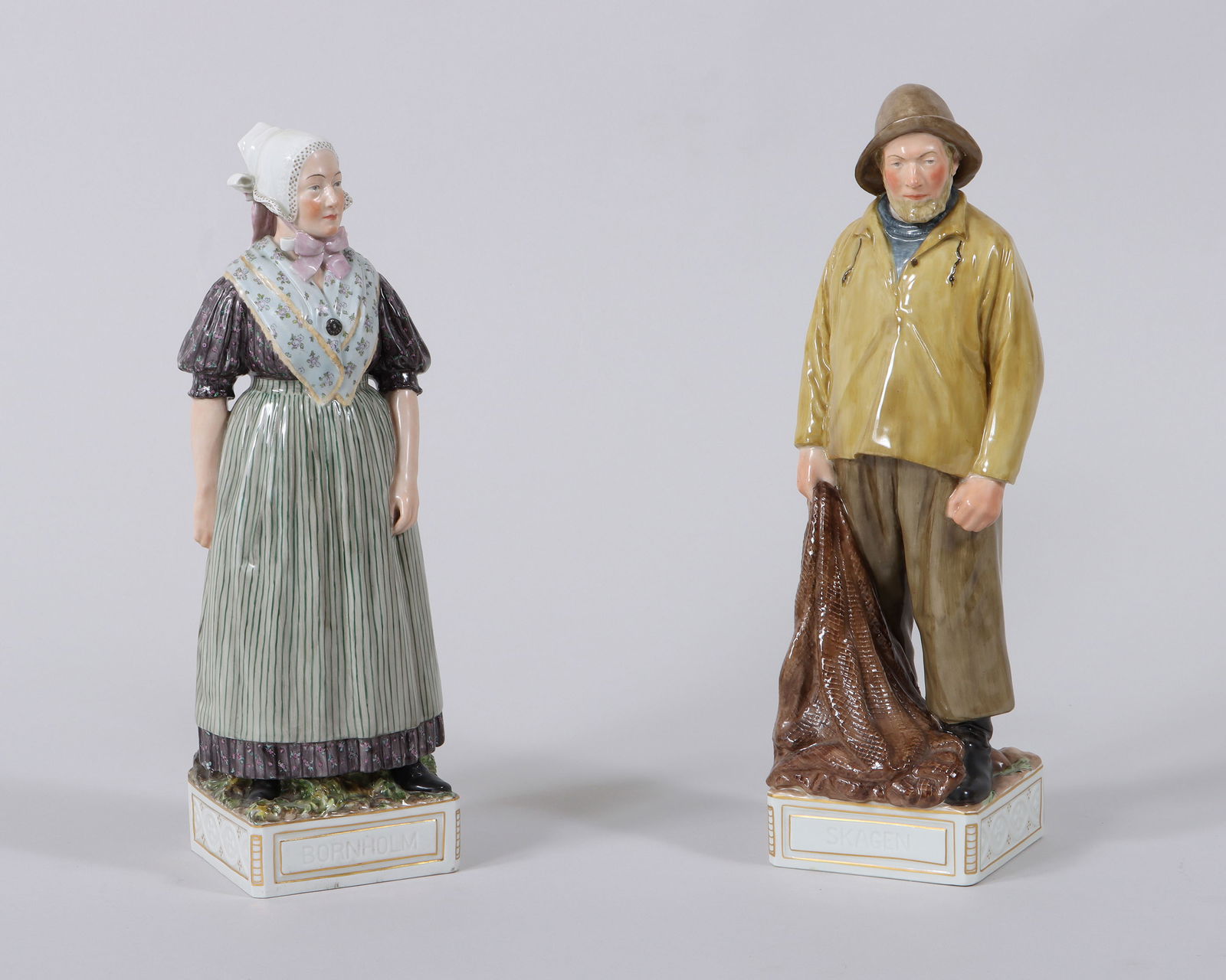 Royal Copenhagen Porcelain Figures: Group of (2) Royal Copenhagen Porcelain Figuresdesigned by Carl Martin Hansen (Danish, 1877-1941), from the "National Costume" series, the hand-painted figures atop square bases with canted corners, f