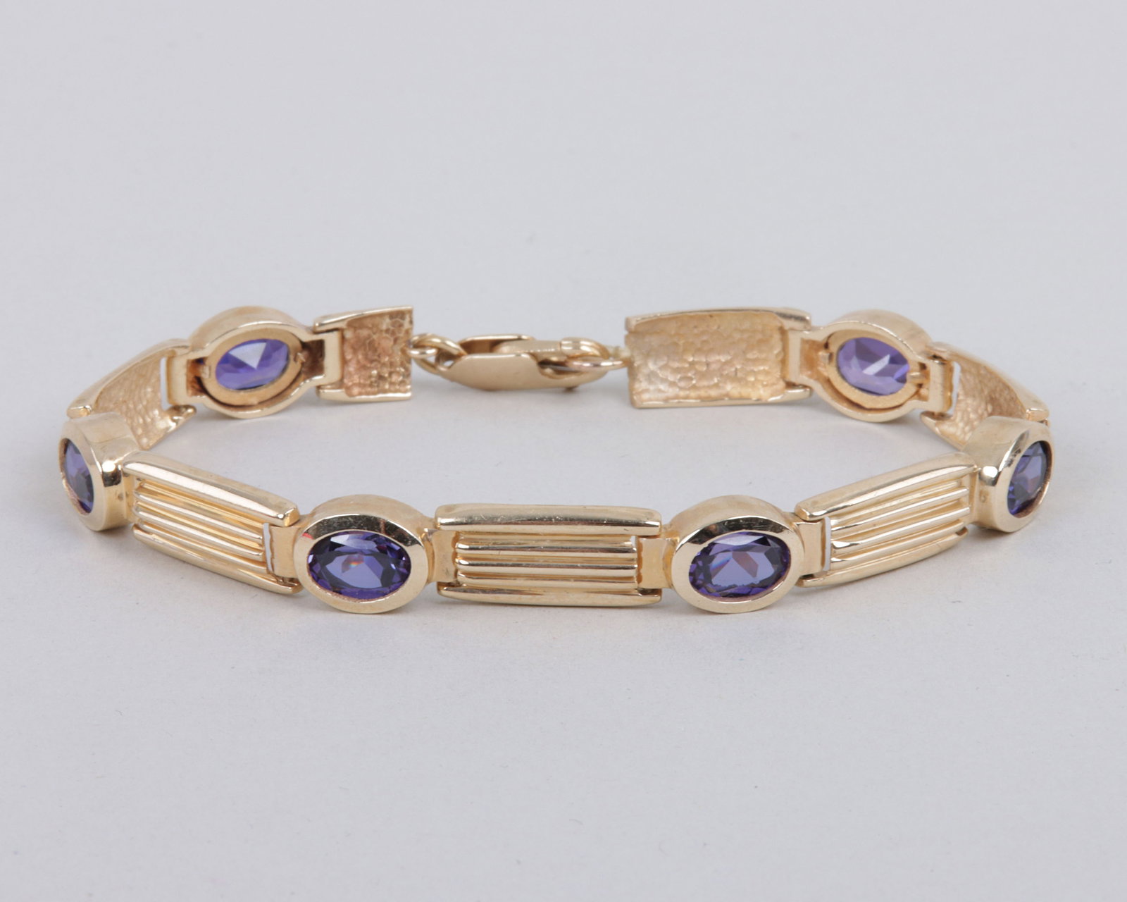 14k Gold Purple Sapphire Bracelet: 14k Gold Purple Sapphire Bracelethaving (6) oval-cut purple sapphires in bezel settings, alternating with ribbed rectangular chain links, marked on clasp; along with a partial chain link.Length (open)