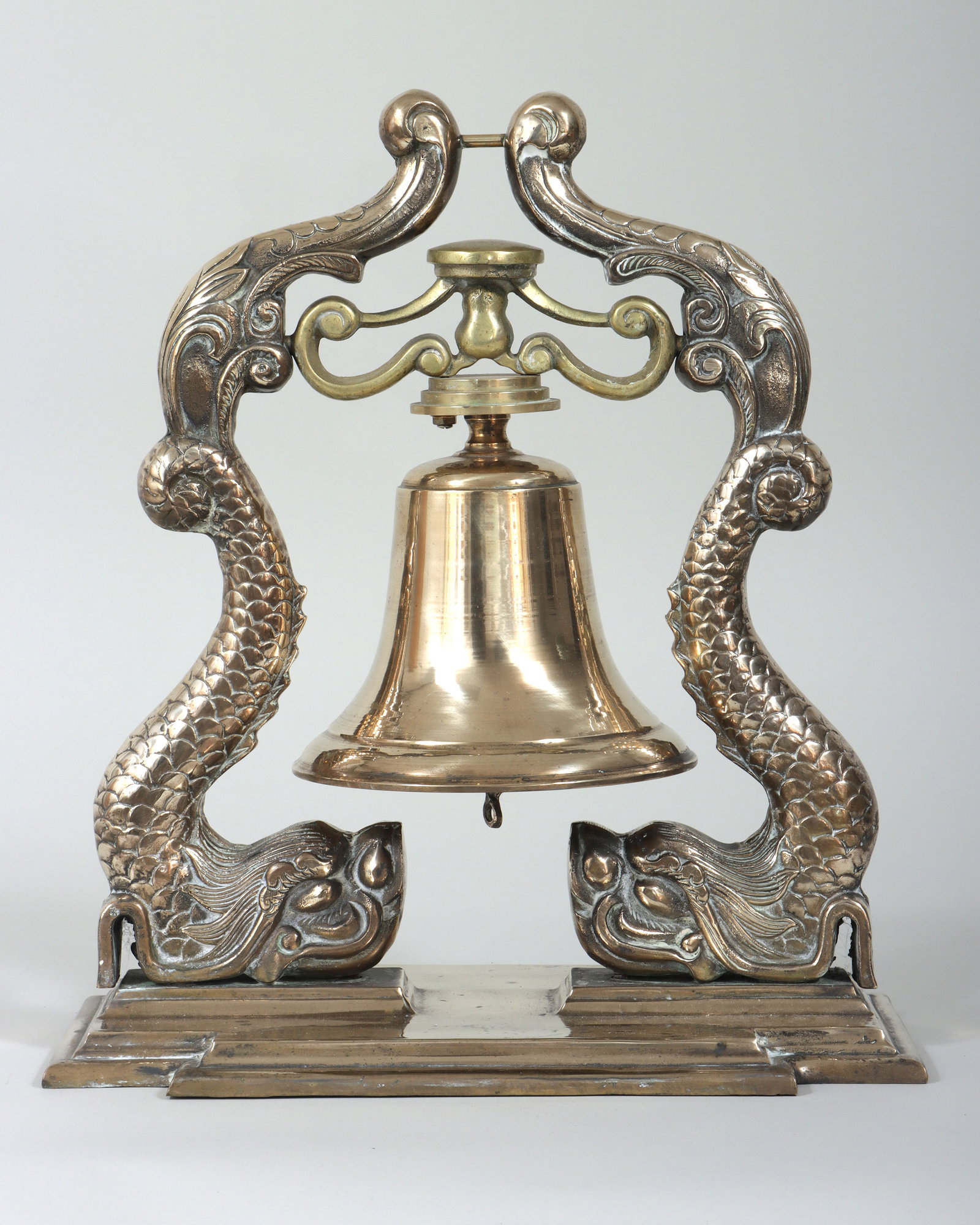 Brass Ship's Bell on Dolphin Base: Brass Ship's Bell on Dolphin Base suspended from scrolled supports with Acanthus leaves and dolphins, on a stepped rectangular base with canted corners, unmarked. Overall 18 x 16 x 9 1/2 in. (45.7 x 4