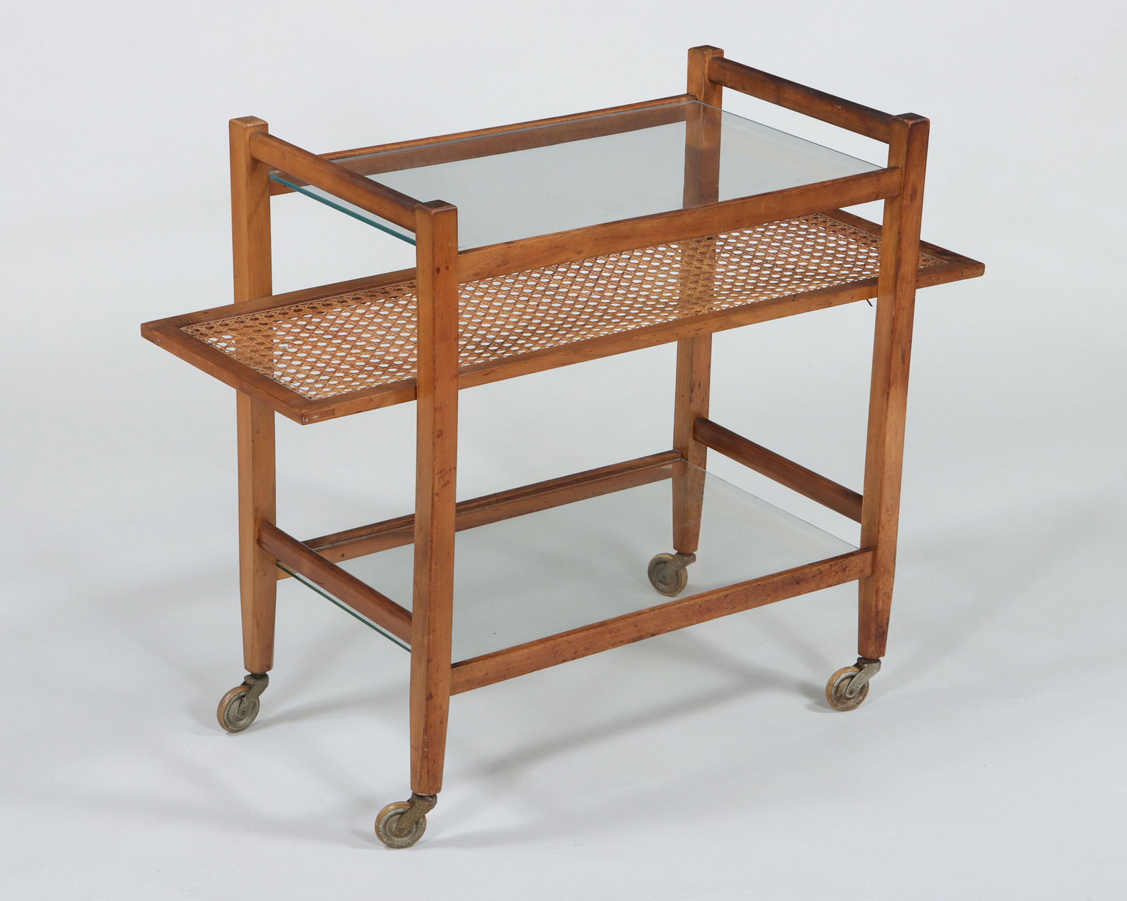 Attributed to Julius Jirasek (Austrian, 1896-1965): Attributed to Julius Jirasek Austrian, 1896-1965 for Werkstätte Hagenauer Wien Midcentury Modern bar cart having two glass shelves and one caned shelf, on casters. 26 x 33 1/2 x 14 in. (66 x 85.1 x 3