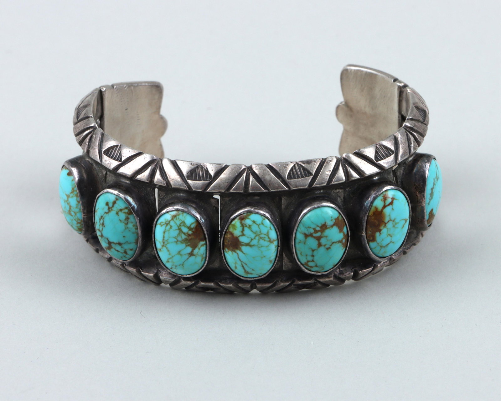Native American Sterling Bracelet: Native American Turquoise and Sterling Silver Cuff Bracelet possibly by Felicita Eustace (Cochiti, 1927-2016), having (7) large turquoise cabochons in bezel settings, borders with geometric design, an