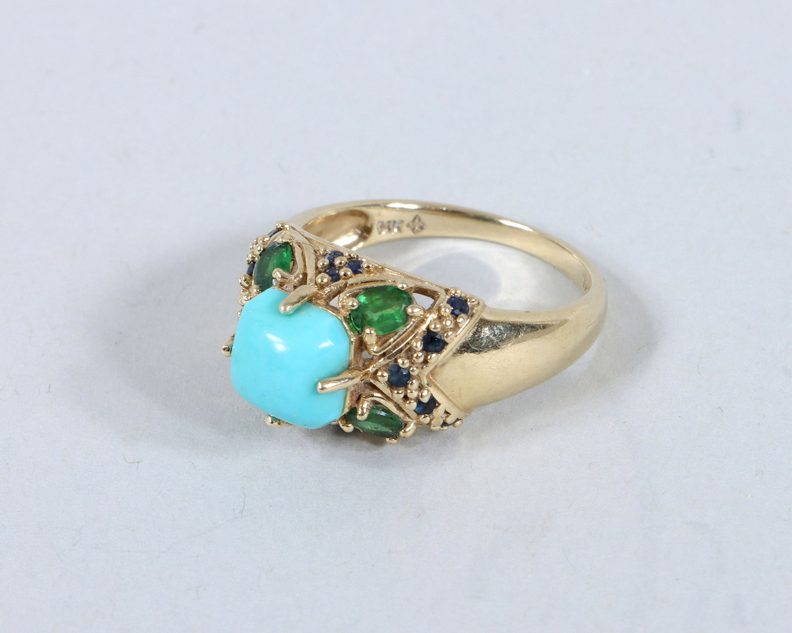 14k Gold Turquoise, Emerald, and Sapphire Ring: 14k Gold Turquoise, Emerald, and Sapphire Ring having a square turquoise cabochon surrounded by (4) oval-cut emeralds and (16) round-cut sapphires, all prong-set in 14k gold, marked inside. Size 9; ap