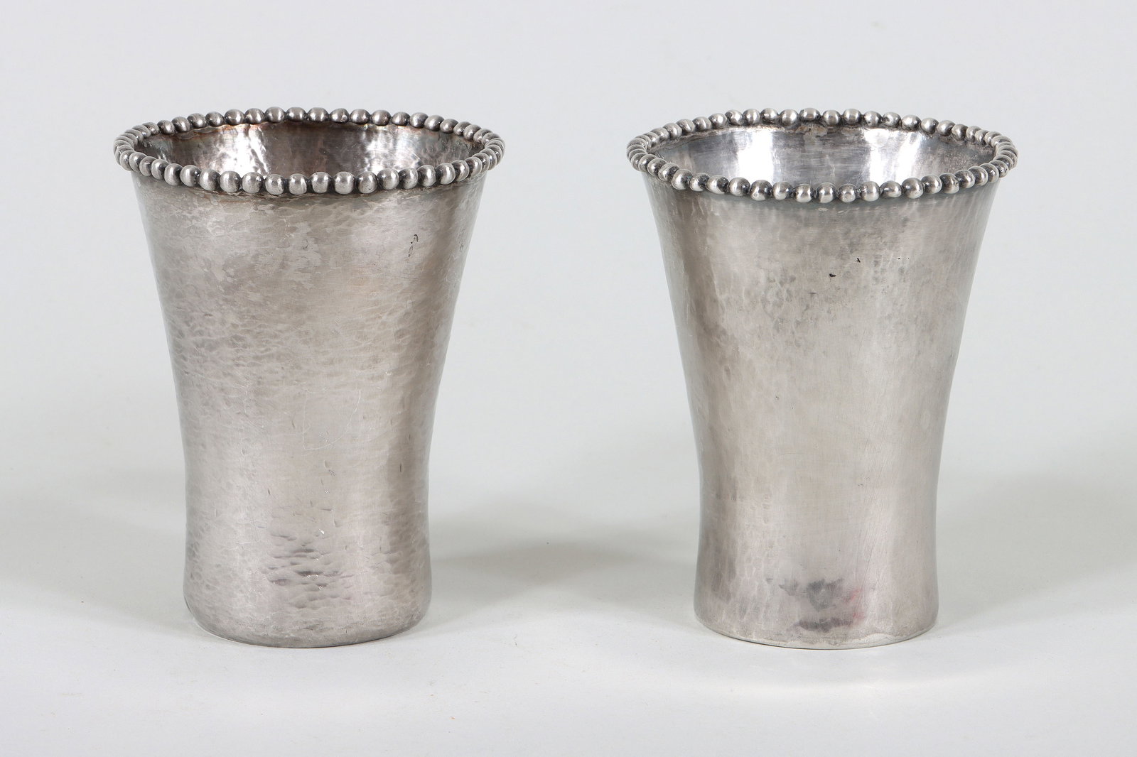 Pair of John Hardy Sterling Beakers: Pair of John Hardy Sterling Silver Beakers the hammered cups having flared openings with applied beaded rims, bottoms marked and with inscription. 4 1/4 in. x 3 1/4 in. dia. (10.8 cm. x 8.3 cm. dia.);