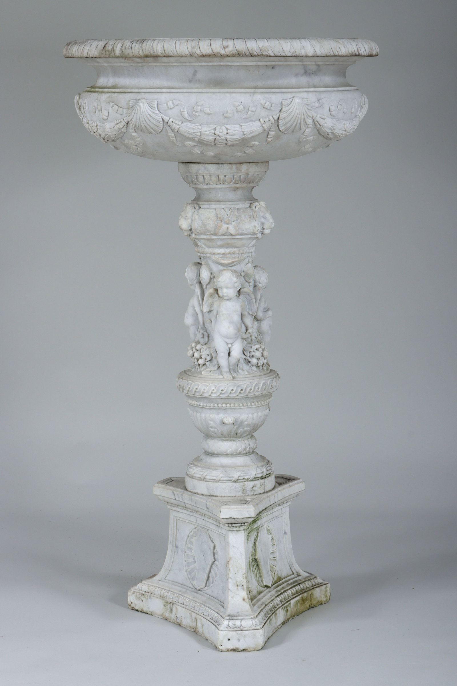Continental Carved Marble Fountain: Continental Carved Marble Fountain in two pieces, the round basin having a leaf-and-dart rim and body with laurel garlands suspended between shell-and-ribbon ties, set on a baluster-form pedestal base