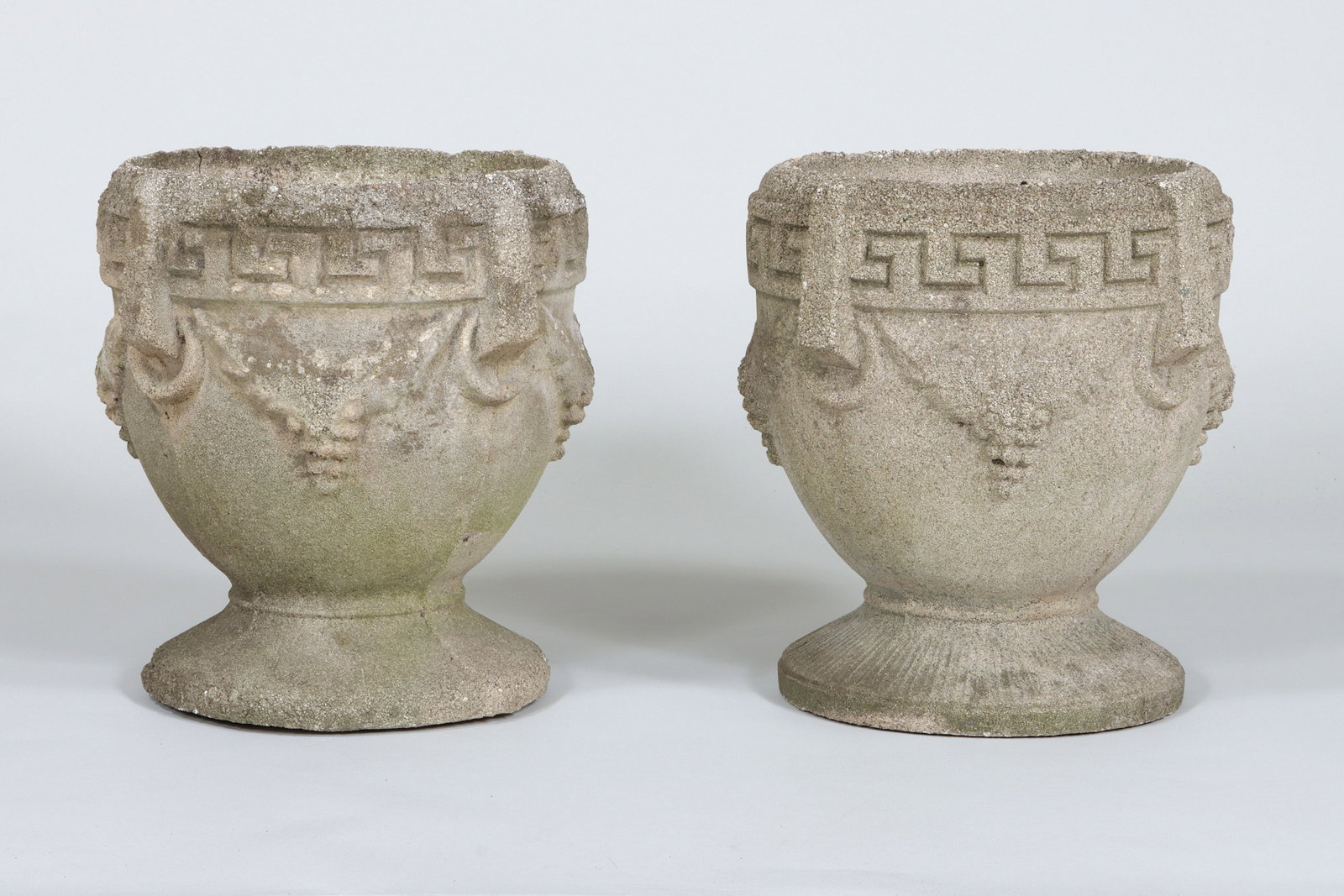 Pair of Small Cast Stone Urns: Pair of Small, Footed Cast Stone Urns with Grape Festoons and Greek Key Designs in Relief 17 x 16 in. (43.2 x 40.6 cm.)