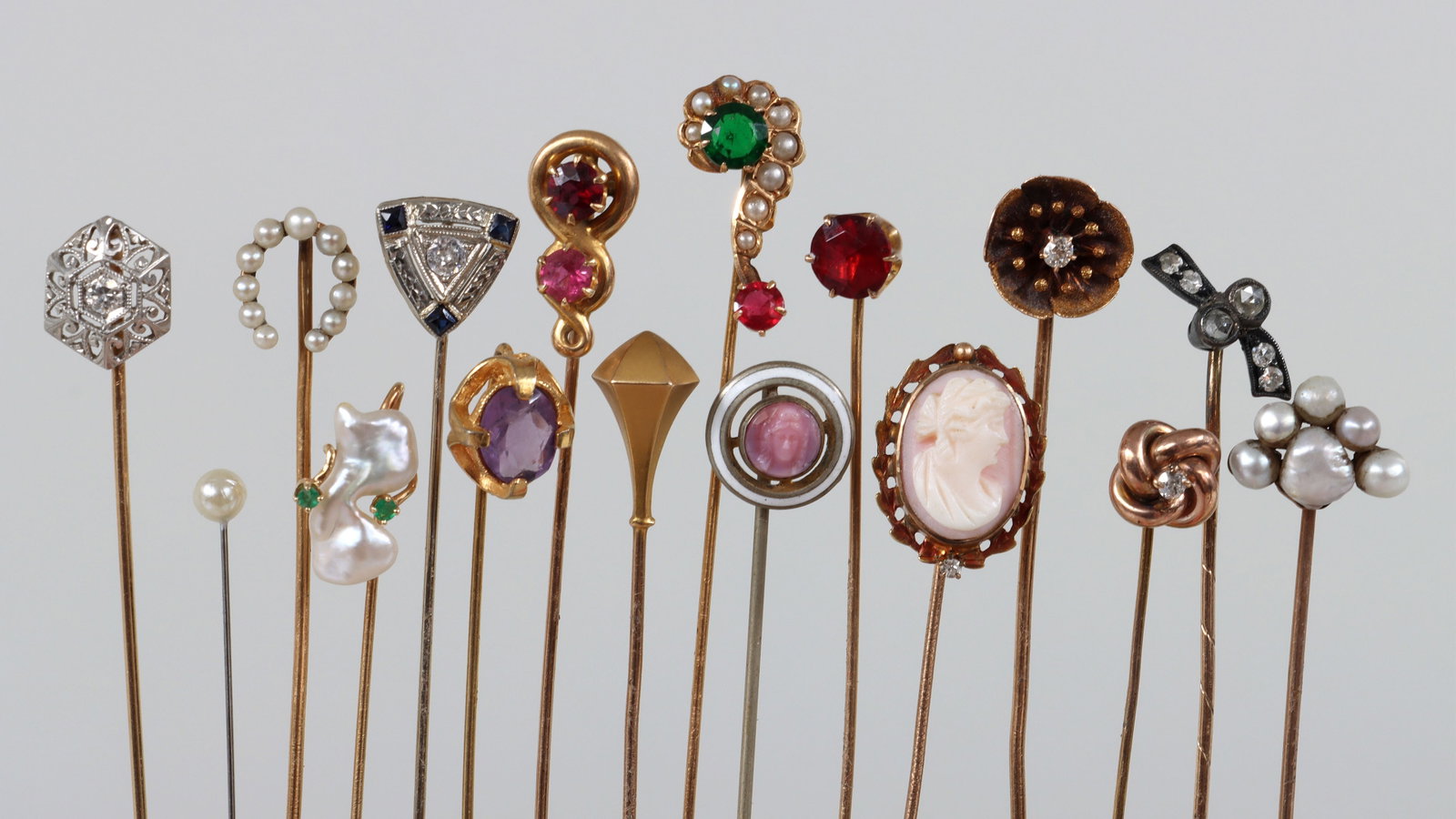 Group of (16) Stickpins: Group of (16) Stickpins to include: white gold and precious stones stickpin, with a round-cut diamond prong-set on an 18k triangle with millegrain detail, surrounded by (3) square-cut sapphires and 18
