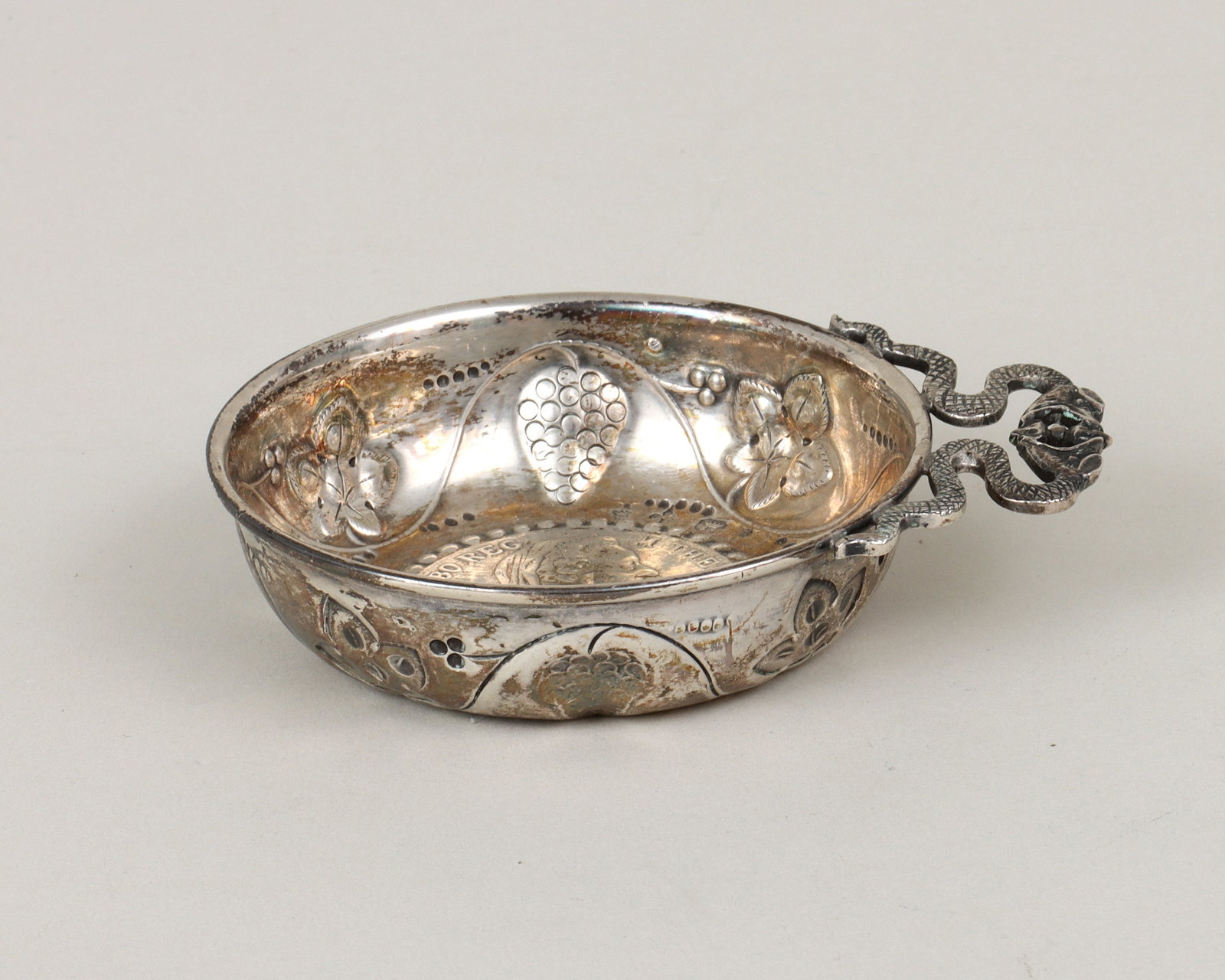 Continental .800 Silver Wine Tasting Cup: Continental .800 Silver Wine Tasting Cup with an inlaid Austrian one-thaler silver coin, dated "1780", surrounded by a repousse beaded border and a repousse and chased grapevine, and having an applied