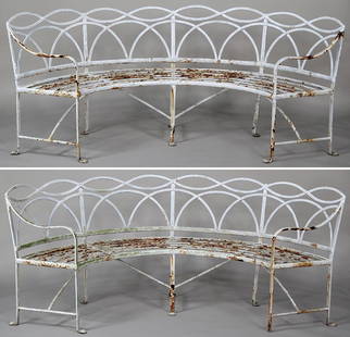 Pair of large curved wrought iron garden benches with: Pair of large curved wrought iron garden benches with open arched and twisted ribbon back rest on paw feet, 34''h, 82''w, seats 21''d; one front foot missing. Provenance: Long Island estate of an art