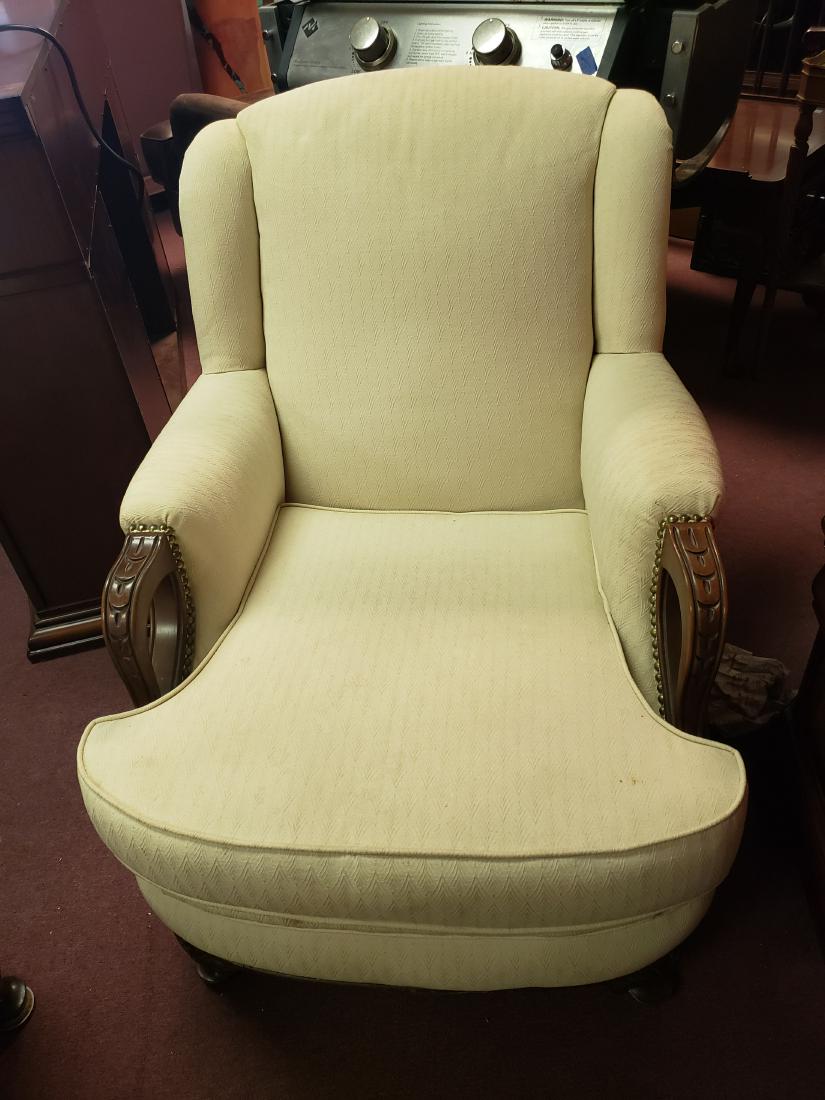 WHITE UPHOLSTERED PARLOR CHAIR: A lovely white or light cream parlor chair, sink into and lean back on. You will want to stay a while and so will your guests on this lovely piece. Wood trim at end of arm area and wood legs.