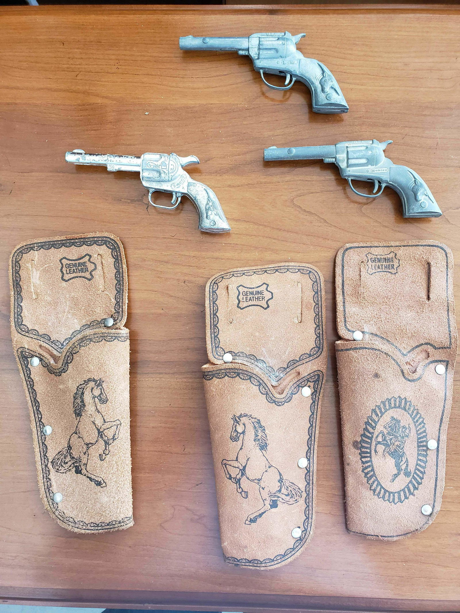 DAISY, HUBLEY, SMOKY JOE TOY GUNS & 3 LEATHER HOLSTERS: These are toy cap guns, included are three genuine leather holsters. The Hubley toy cap gun/pistol dates from 1920 to 1965. This appears to be a mold that the cap gun manufacturers used.