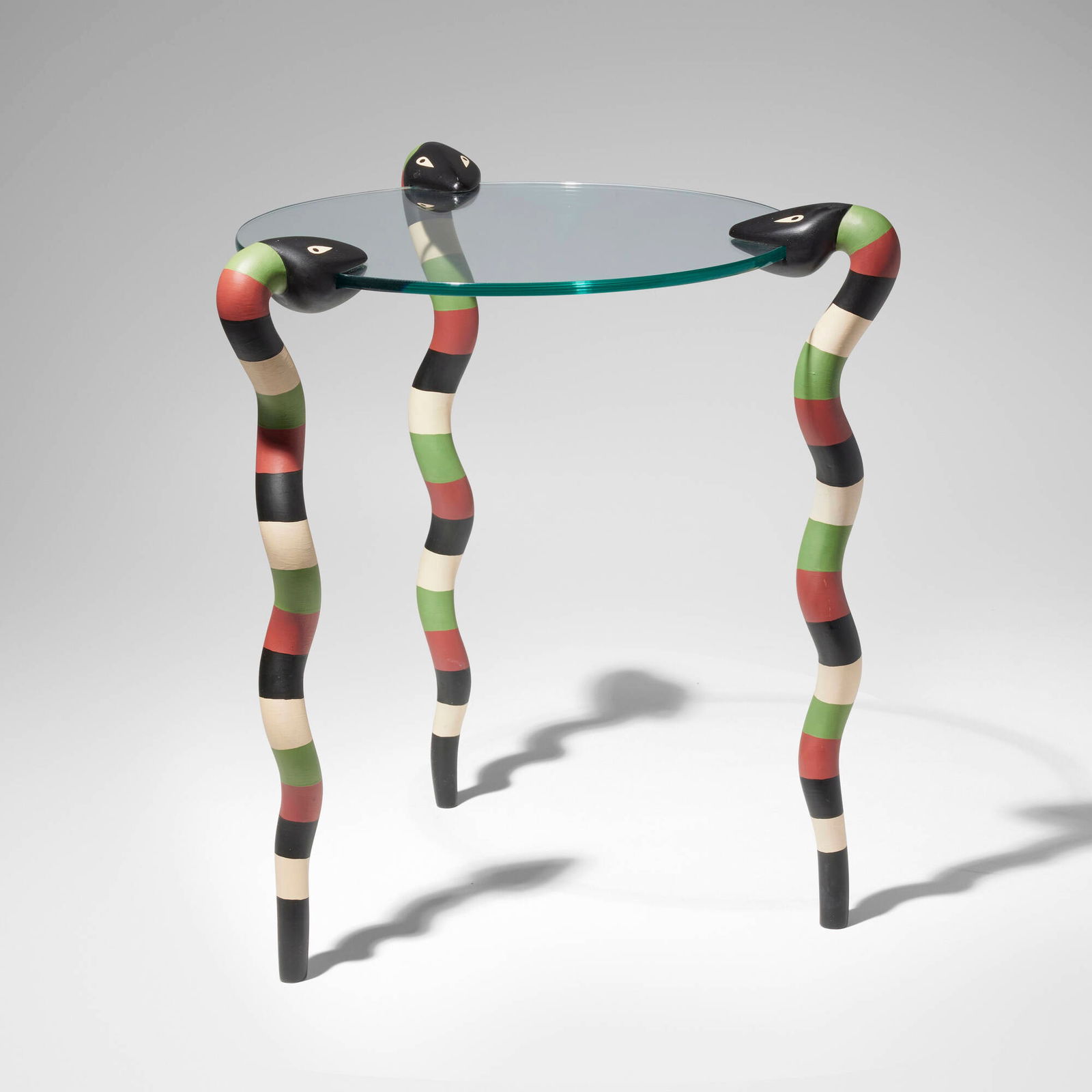 Judy Kensley McKie, Snake table: Judy Kensley McKie Snake table USA, 1988glass, painted wood 21.5 h x 19 dia in (55 x 48 cm) Signed and dated to one leg '?JKM 1988'. Sold with a digital copy of the exhibition pamphlet from Th