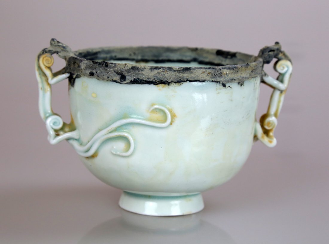 SONG DYNASTY STYLE YINGQING GLAZED CUP.: SONG DYNASTY STYLE YINGQING GLAZED CUP. China. Song dynasty style yingqing glazed cup in lotus form decorated with two dragon, The cup edge decorated with silver . Measure: Height 2.75 ", diameter of 