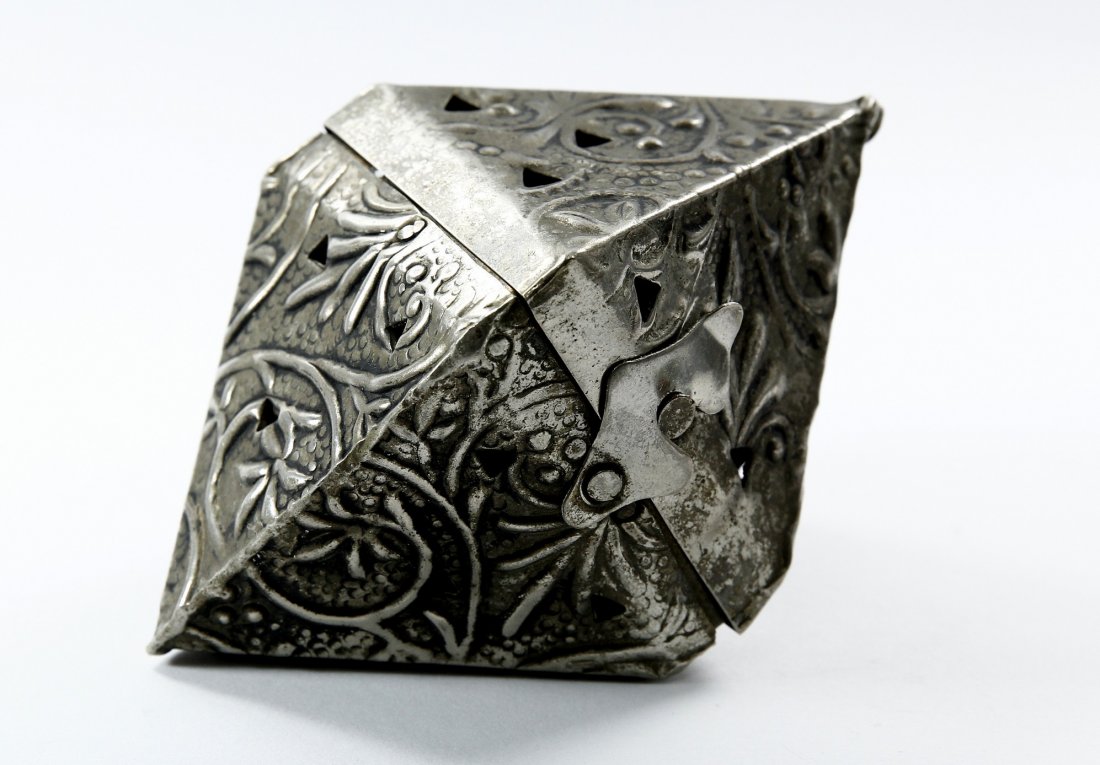 Spice Holder. Sukka Decoration? Beginning of the 20th: Metal, diamond-shaped spice holder. Opens with a hinge. Hanging ring. Apparently hung in the sukka. 13 cm. tall. Fine condition.